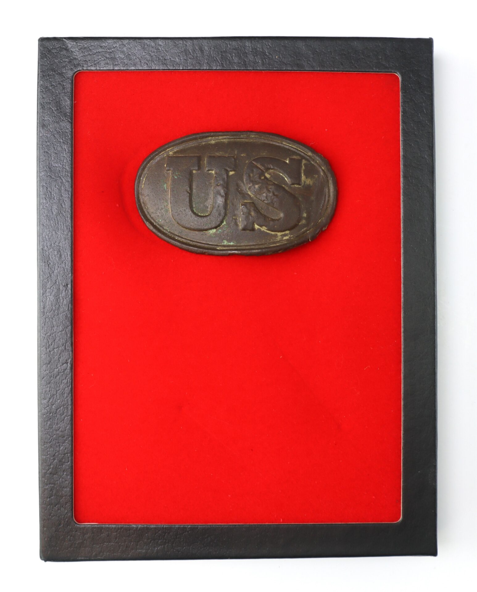 A bronze "US" military belt buckle displayed in a black frame with a red background.