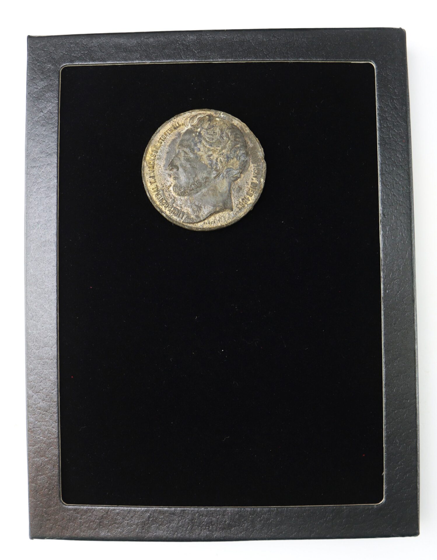 A single ancient coin with a profile portrait, displayed on a black velvet background in a rectangular frame.