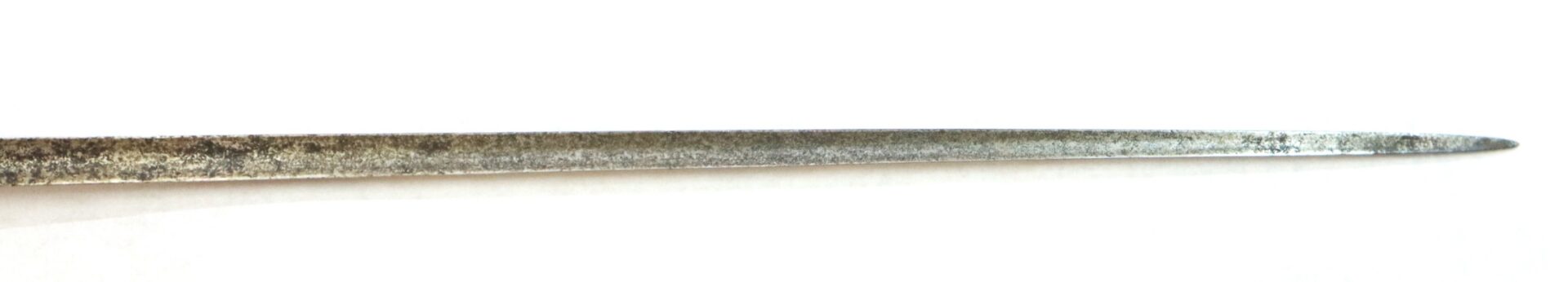 Close-up of the pointed tip of a weathered, metallic sword or blade against a white background.