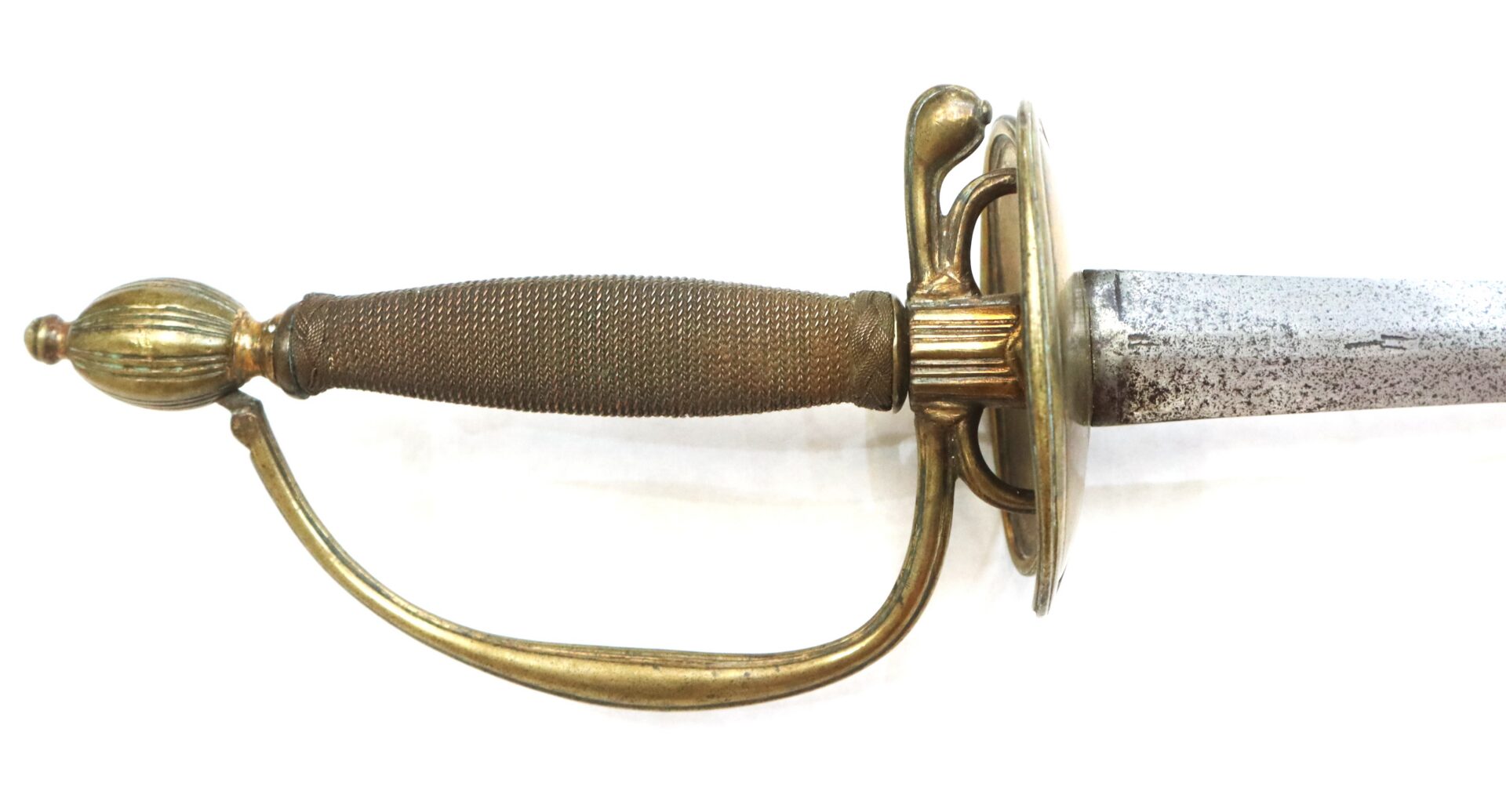 Close-up of a sword with a textured grip, brass handguard, and partially tarnished blade against a white background.