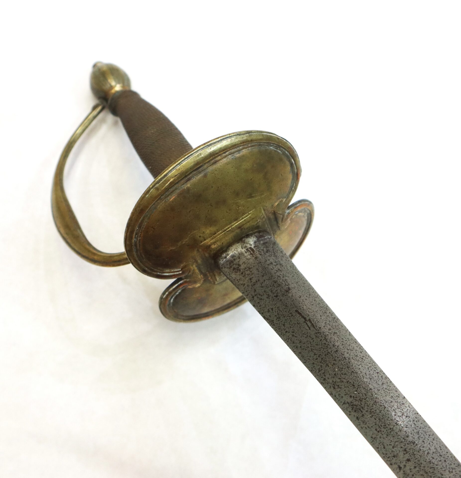 A close-up of an antique sword with a brass hilt, wire-wrapped grip, and a tarnished, straight steel blade on a white background.