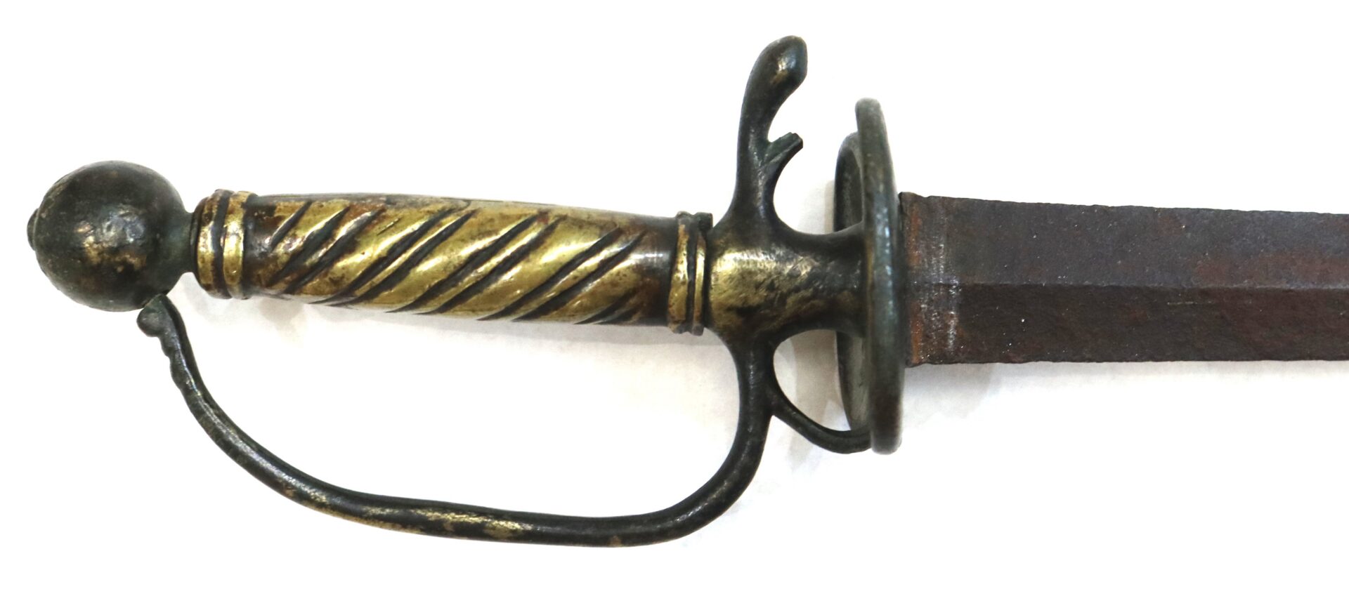 Close-up of an antique sword hilt with a brass and black twisted handle, rounded pommel, and a rusty blade against a white background.