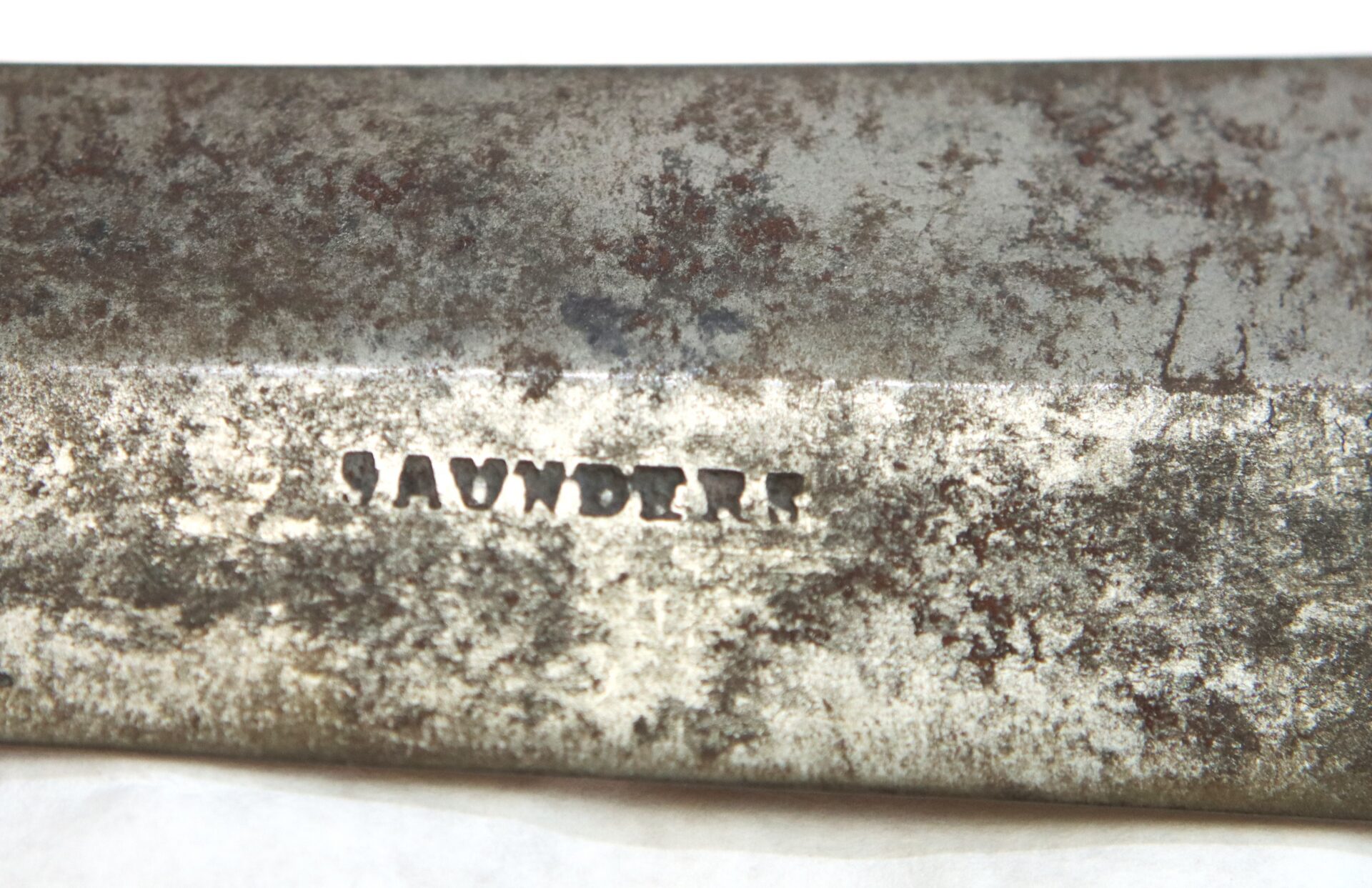 A close-up of a rusty metal surface with the word "SAUNDERS" stamped into it.
