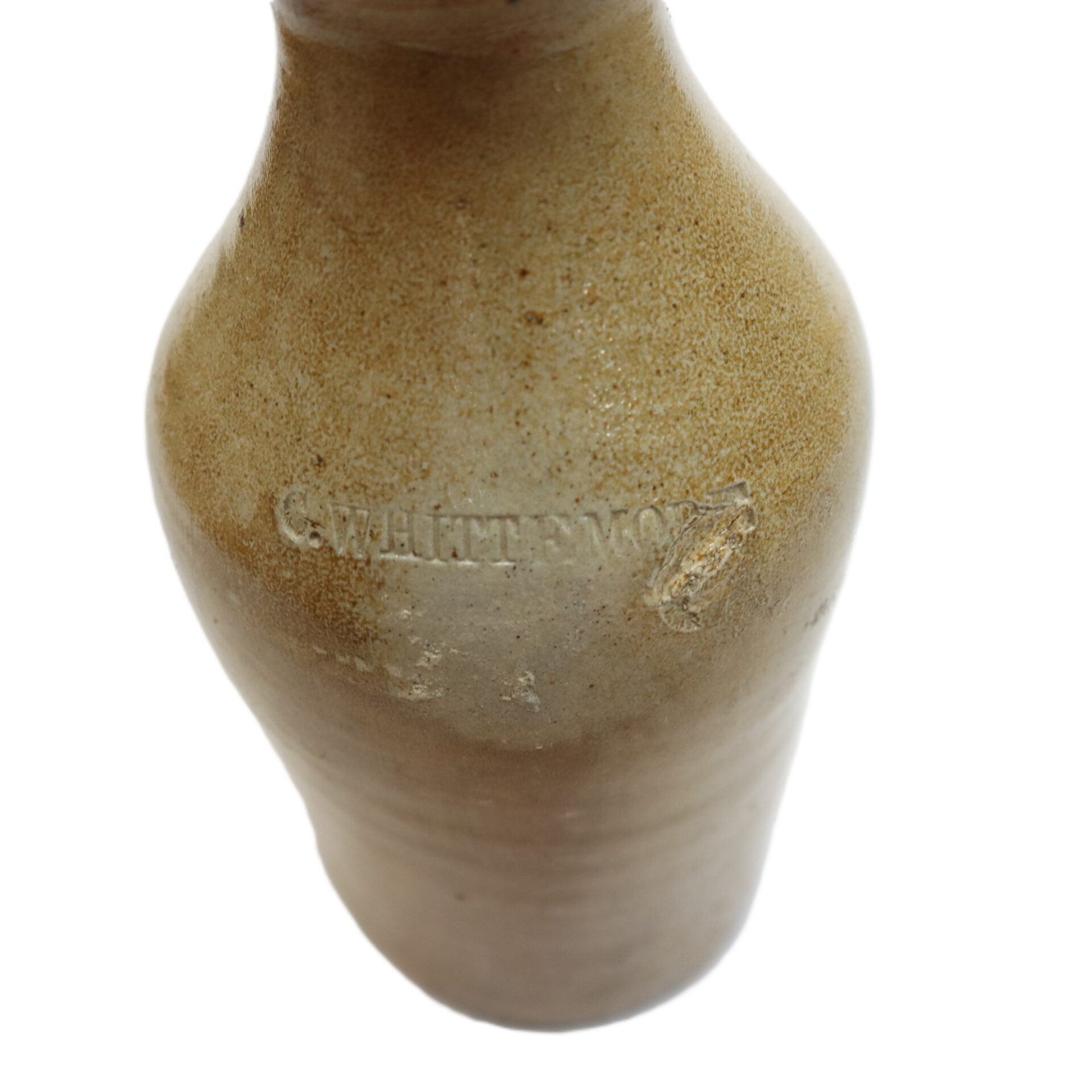 A brown ceramic bottle with a slightly textured surface and the embossed word "WHITTEMORE" on its side.