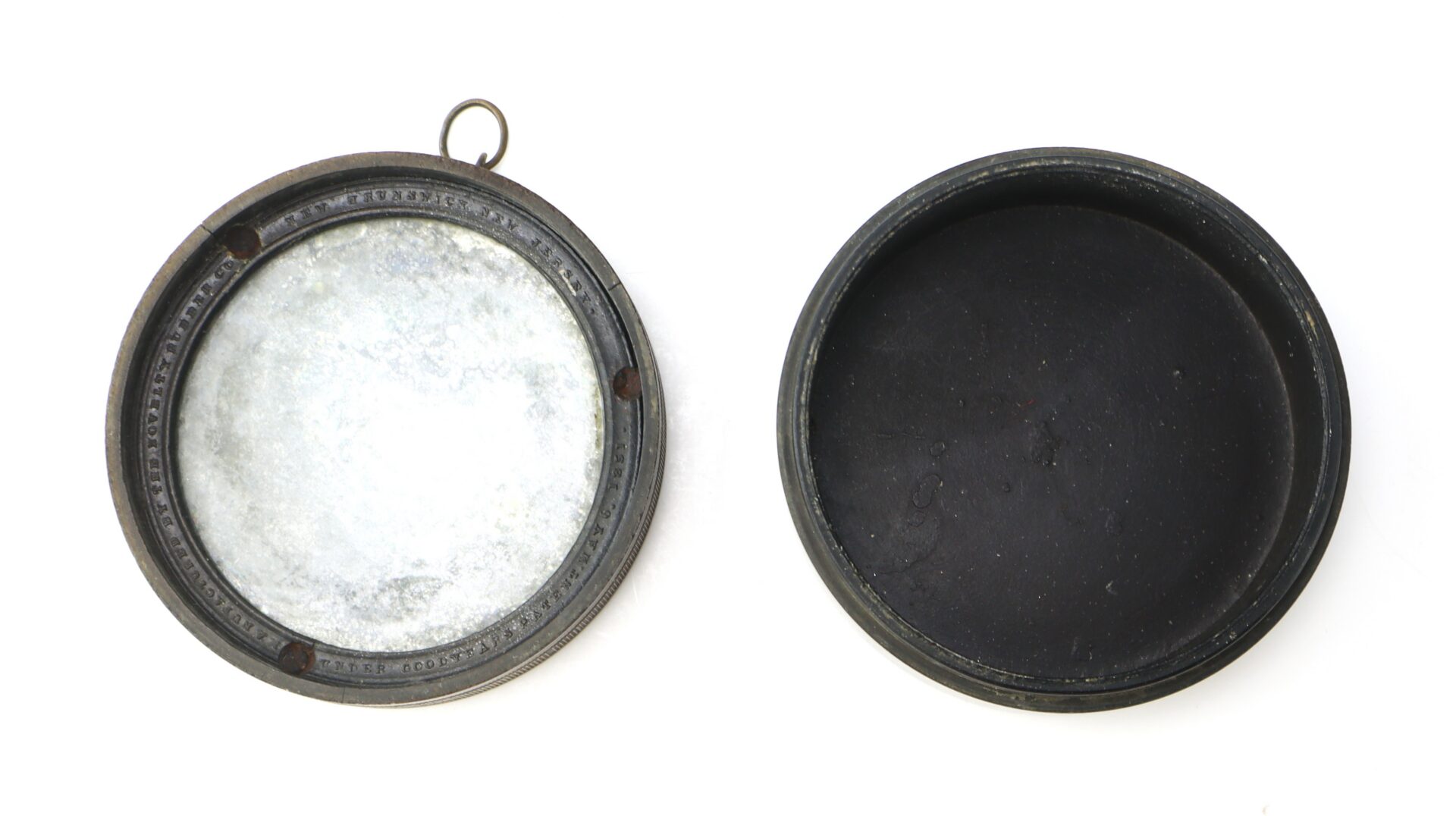 Two round, shallow metal containers are shown side by side; one with a metallic interior and a small loop, the other with a black interior.