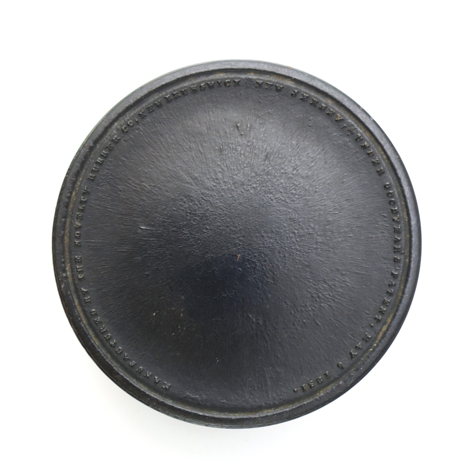 A black, round hockey puck with textured surface and raised lettering around the edge, photographed from above on a white background.