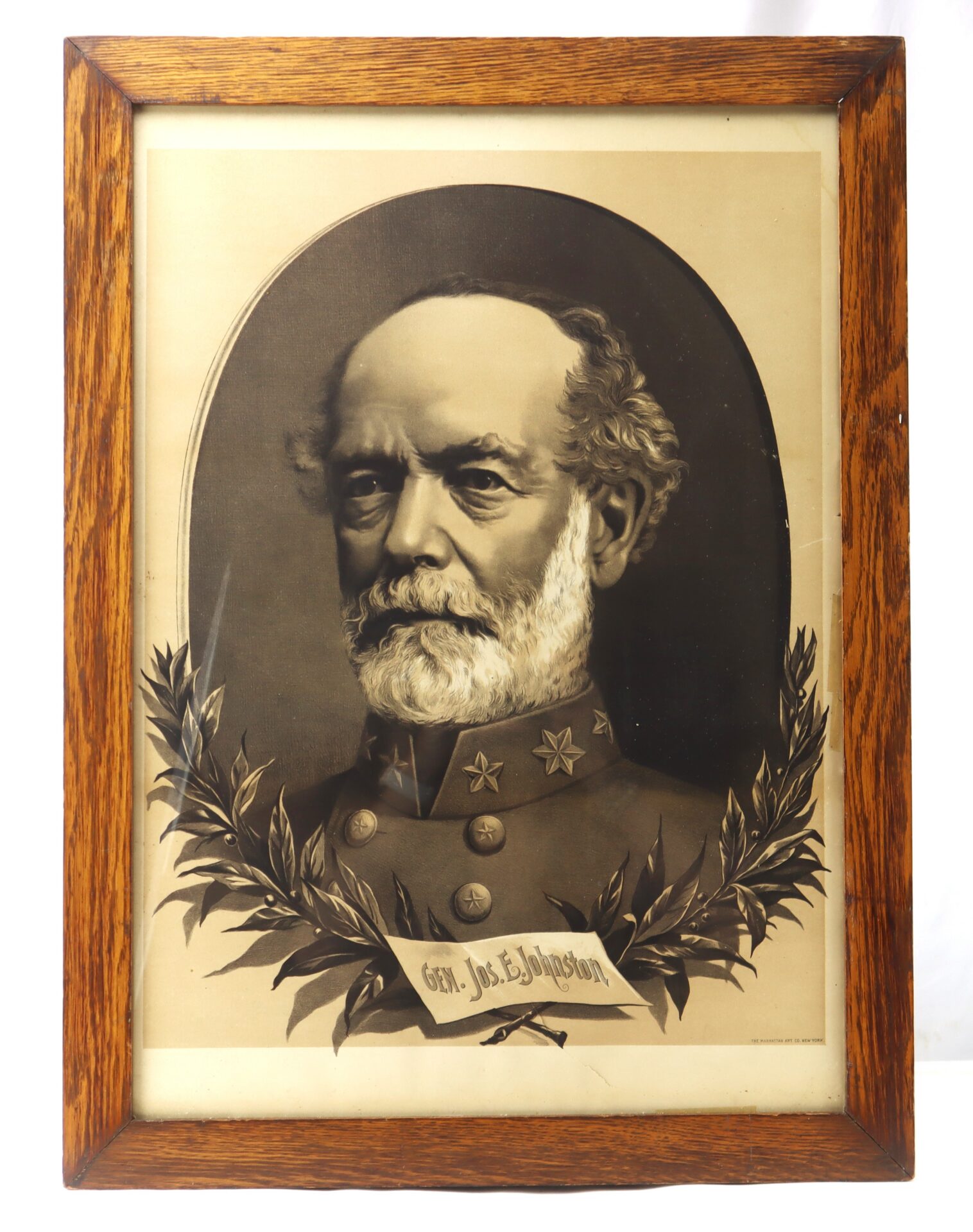 Sepia portrait of a bearded man in a military uniform with three stars, framed in wood, with a laurel wreath and a nameplate reading "Gen. J. E. Johnston" at the bottom.