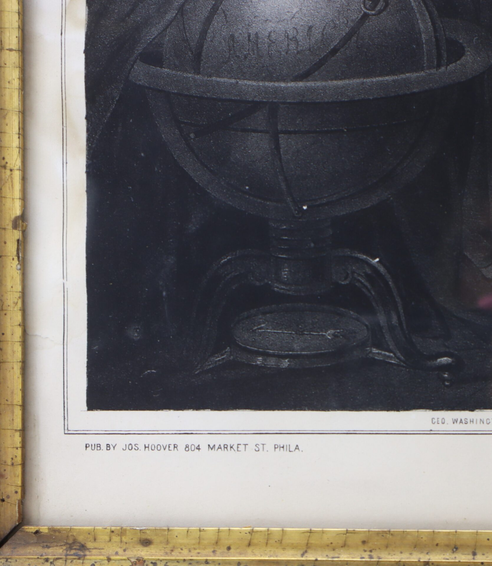 Close-up of a framed image showing a globe model with armillary rings; text below reads "PUB. BY JOS. HOOVER 804 MARKET ST. PHILA.
