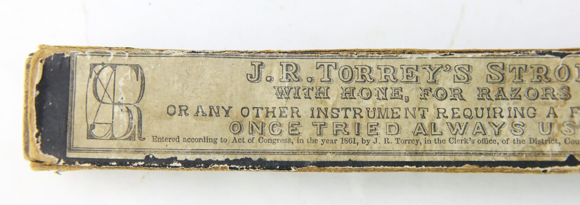 Close-up of a worn vintage box label reading "J.R. Torrey’s Patent Razor Strop, 1861 Dated" with additional product and copyright details.