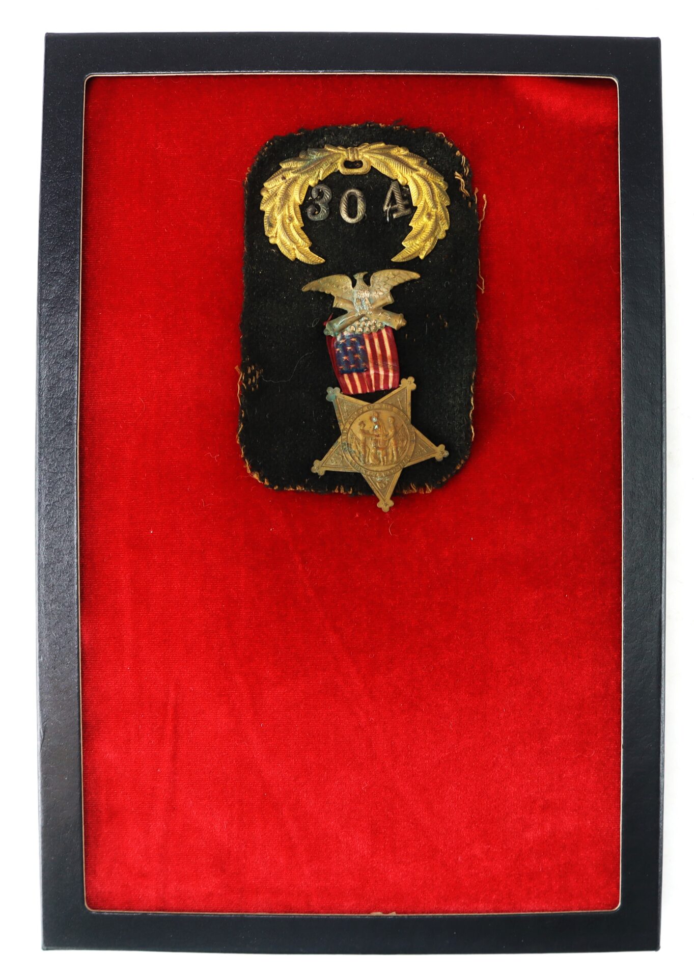 A framed military badge with the number 804, gold laurel, an eagle, American shield, and star medallion displayed on a black patch, mounted on red velvet.