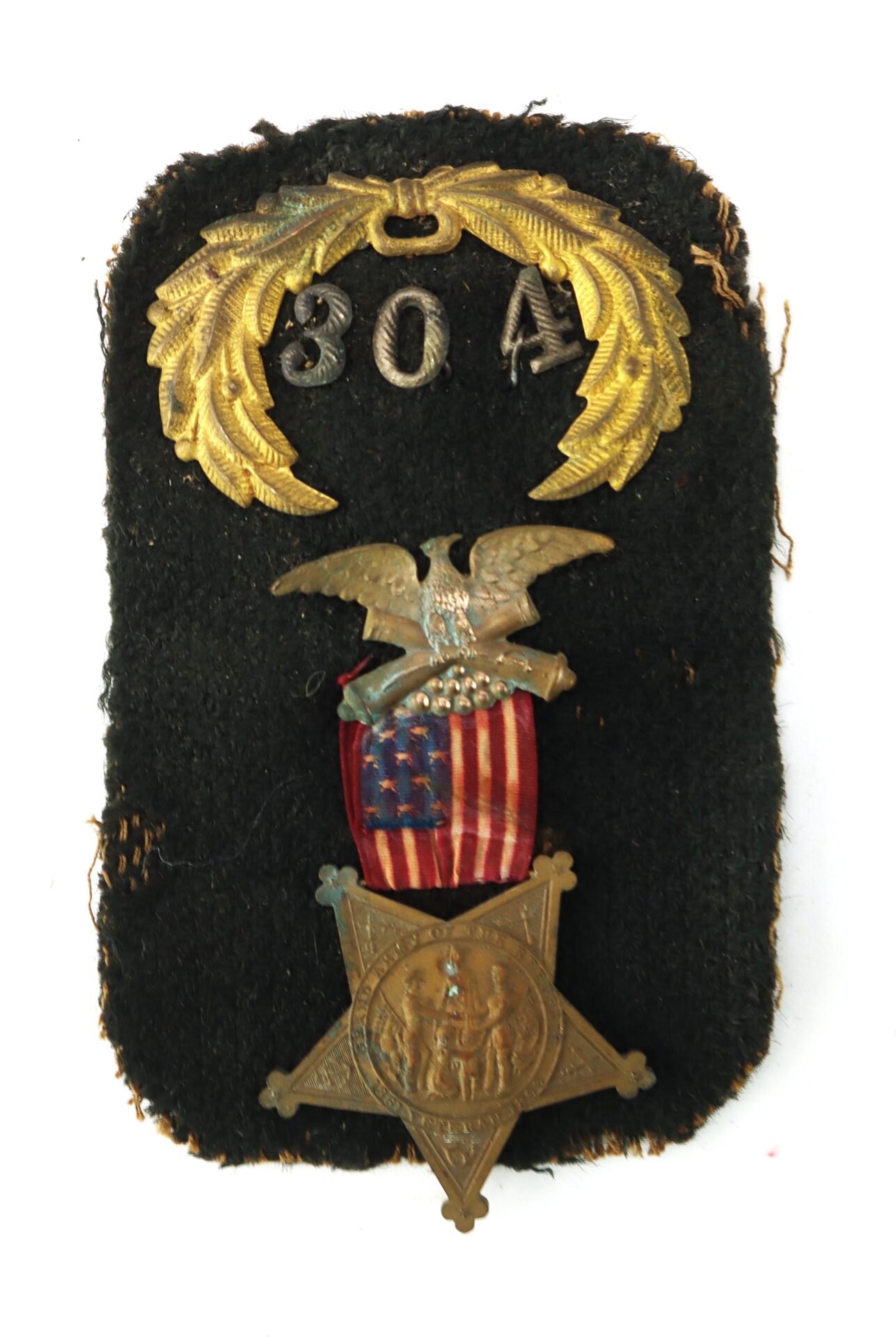 A military badge with a gold laurel and "304" at the top, an eagle over a US flag shield, and a bronze star medal featuring two figures at the bottom, on a black fabric background.