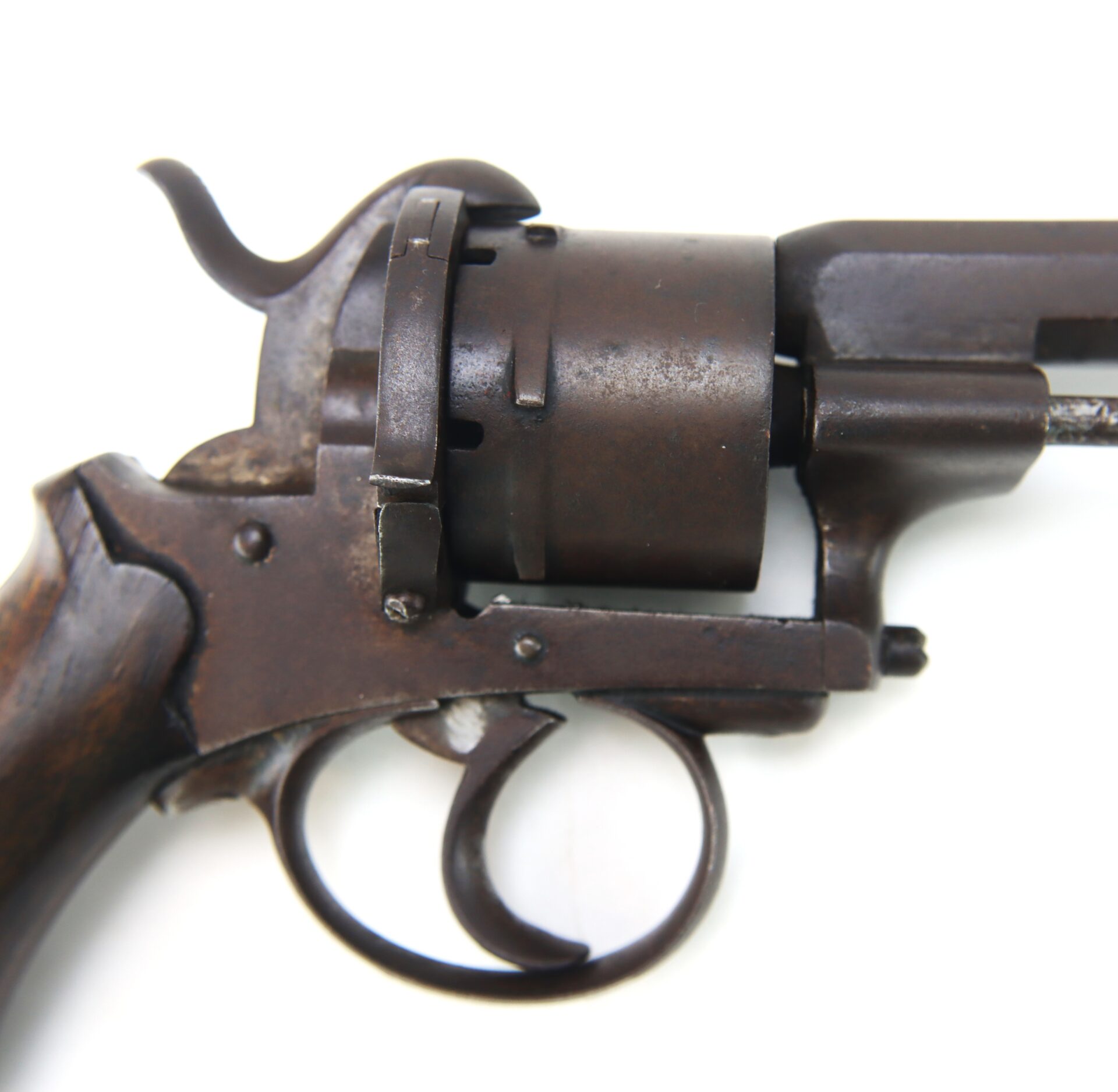 Close-up of an old, rusted revolver focusing on the trigger, cylinder, and part of the handle, set against a white background.