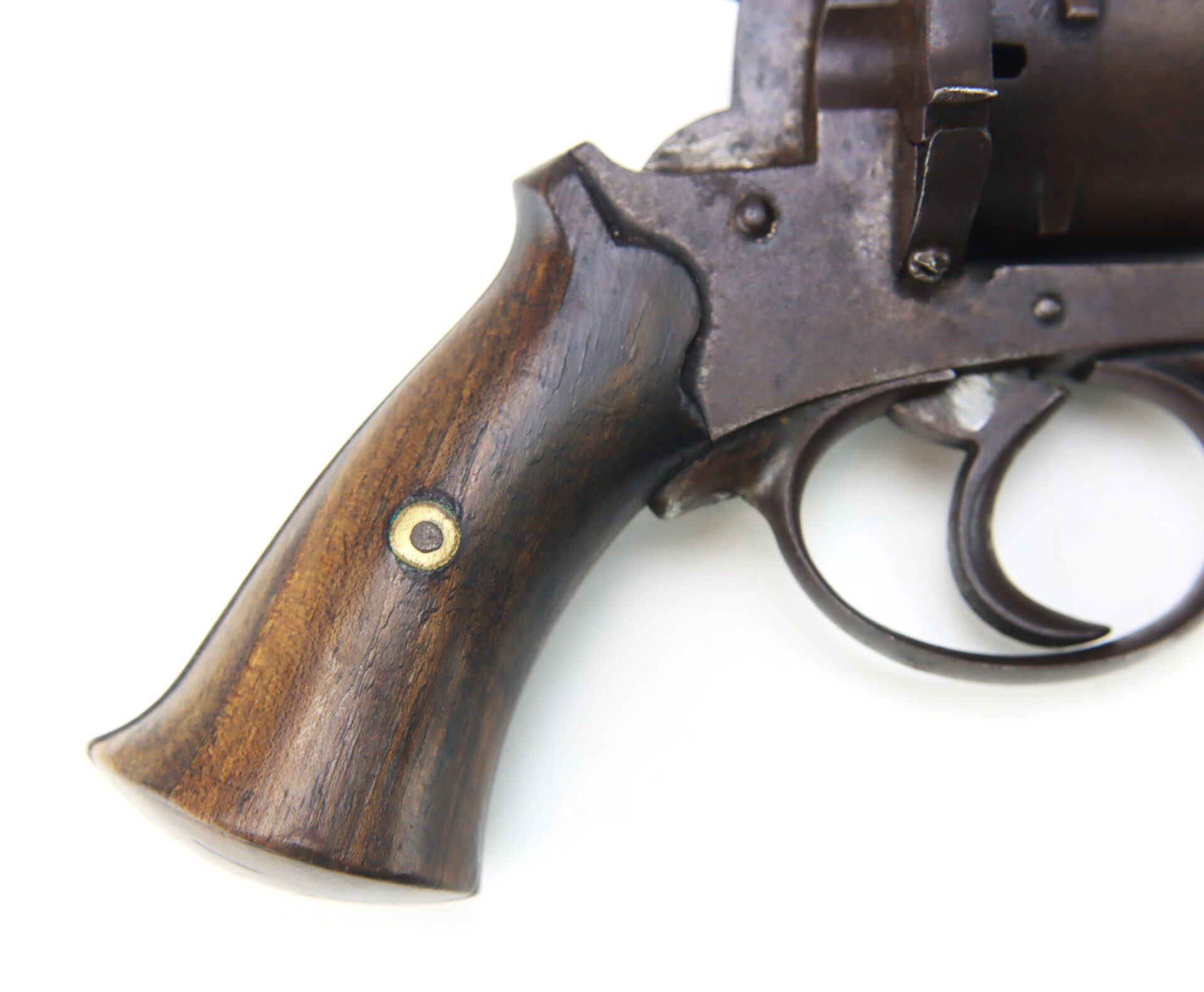 Close-up of the wooden handle and trigger area of an old revolver against a white background.
