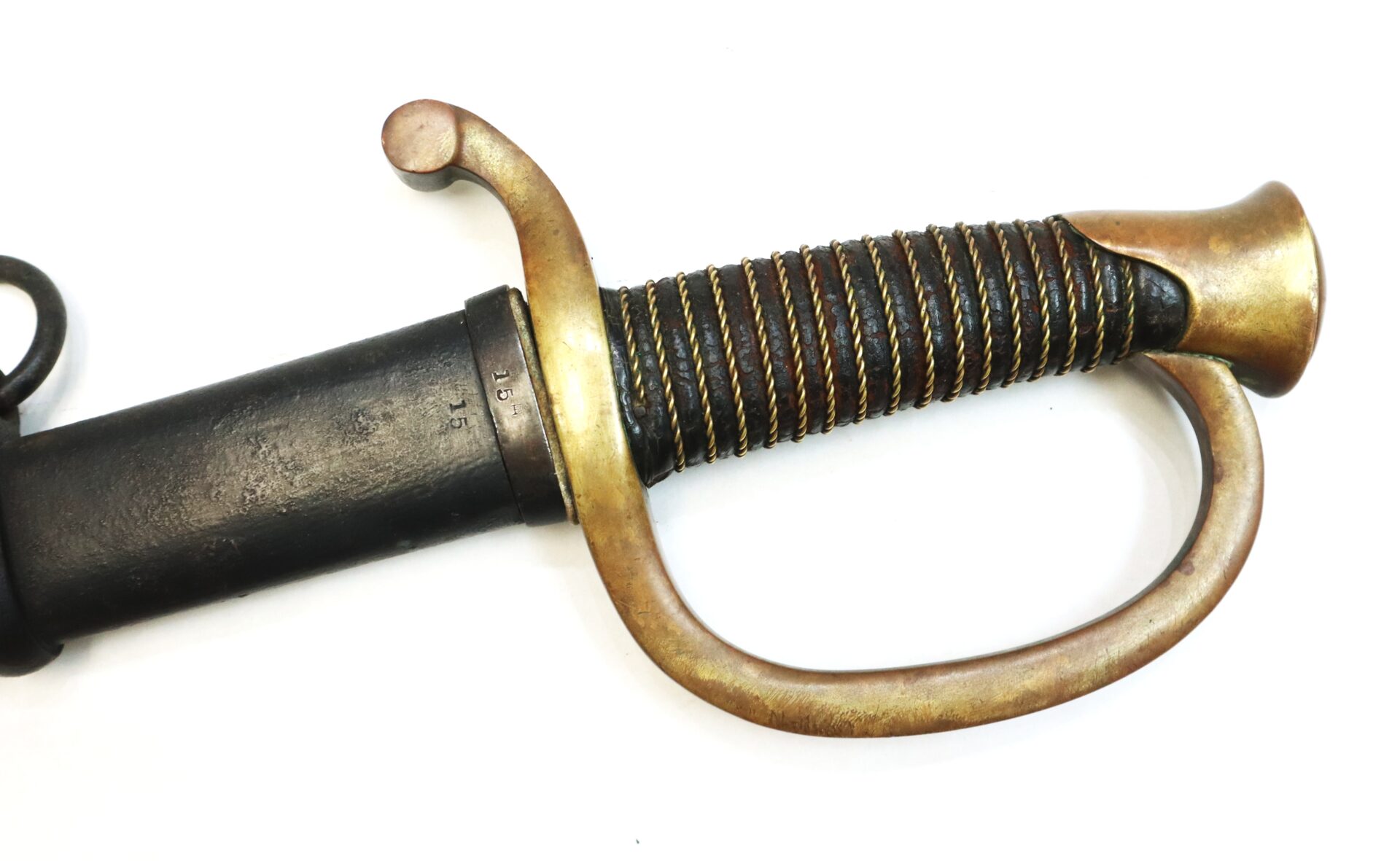 Close-up of a sword hilt with a brass guard and wire-wrapped grip, partially sheathed in a black scabbard, photographed on a white background.