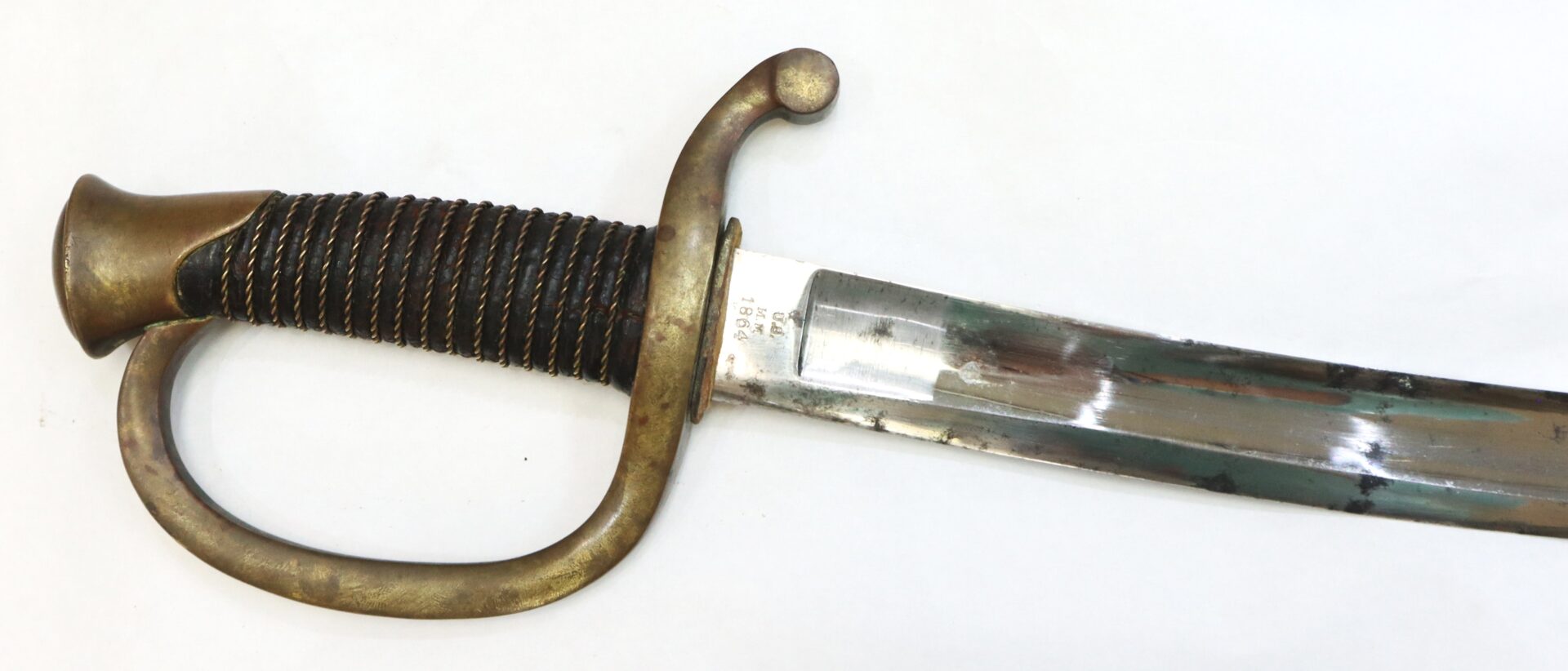 Antique brass-hilted sword with a curved, partially tarnished blade and a grooved grip, photographed against a plain white background.