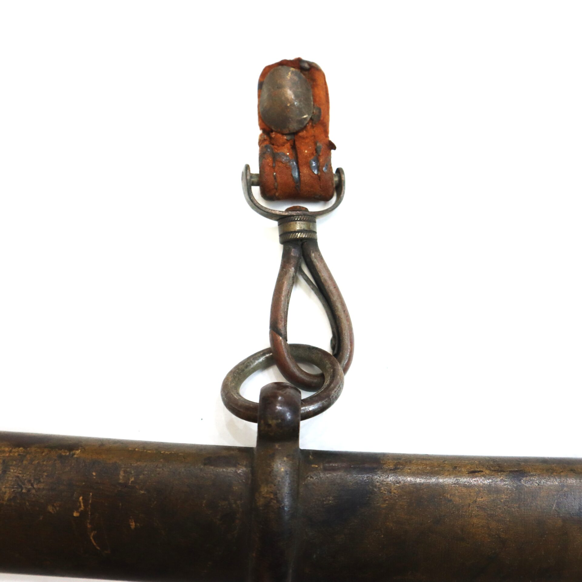 Close-up of a worn metal and leather swivel hook attached to a metal rod or bar, showing signs of rust and age.