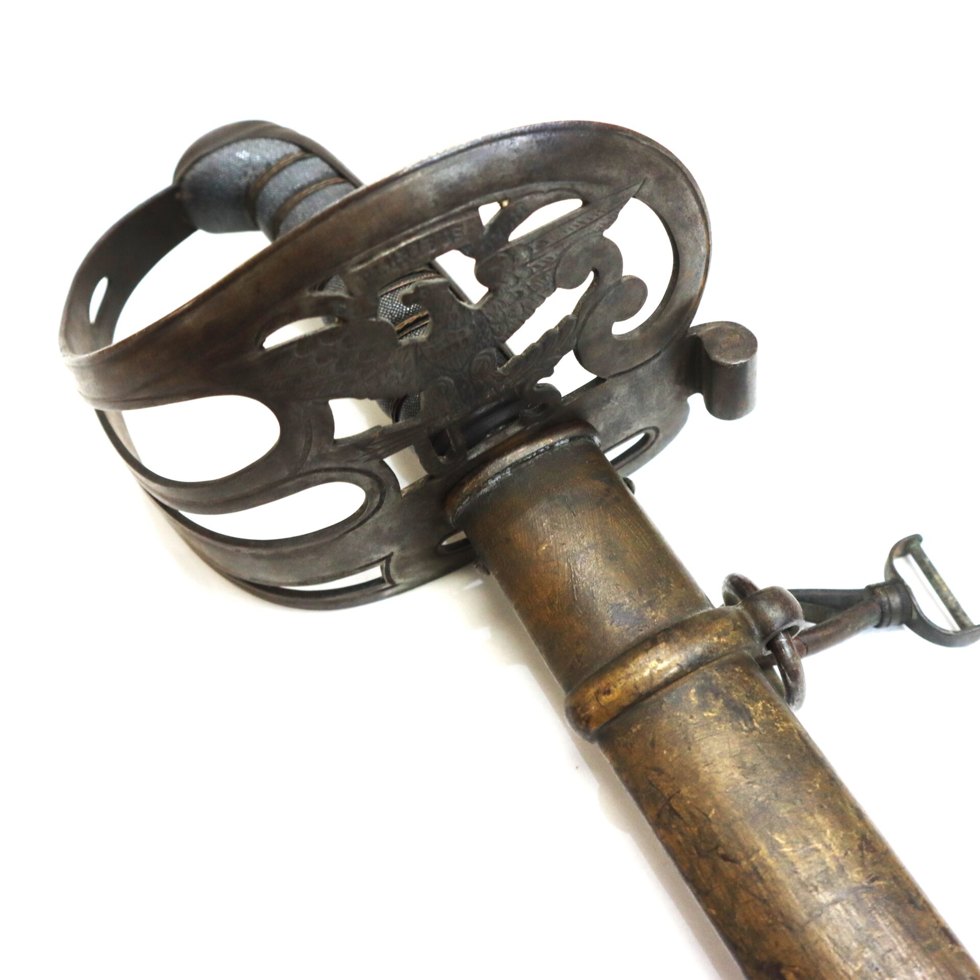 Close-up of an antique sword with an ornate metal guard and a weathered scabbard against a white background.