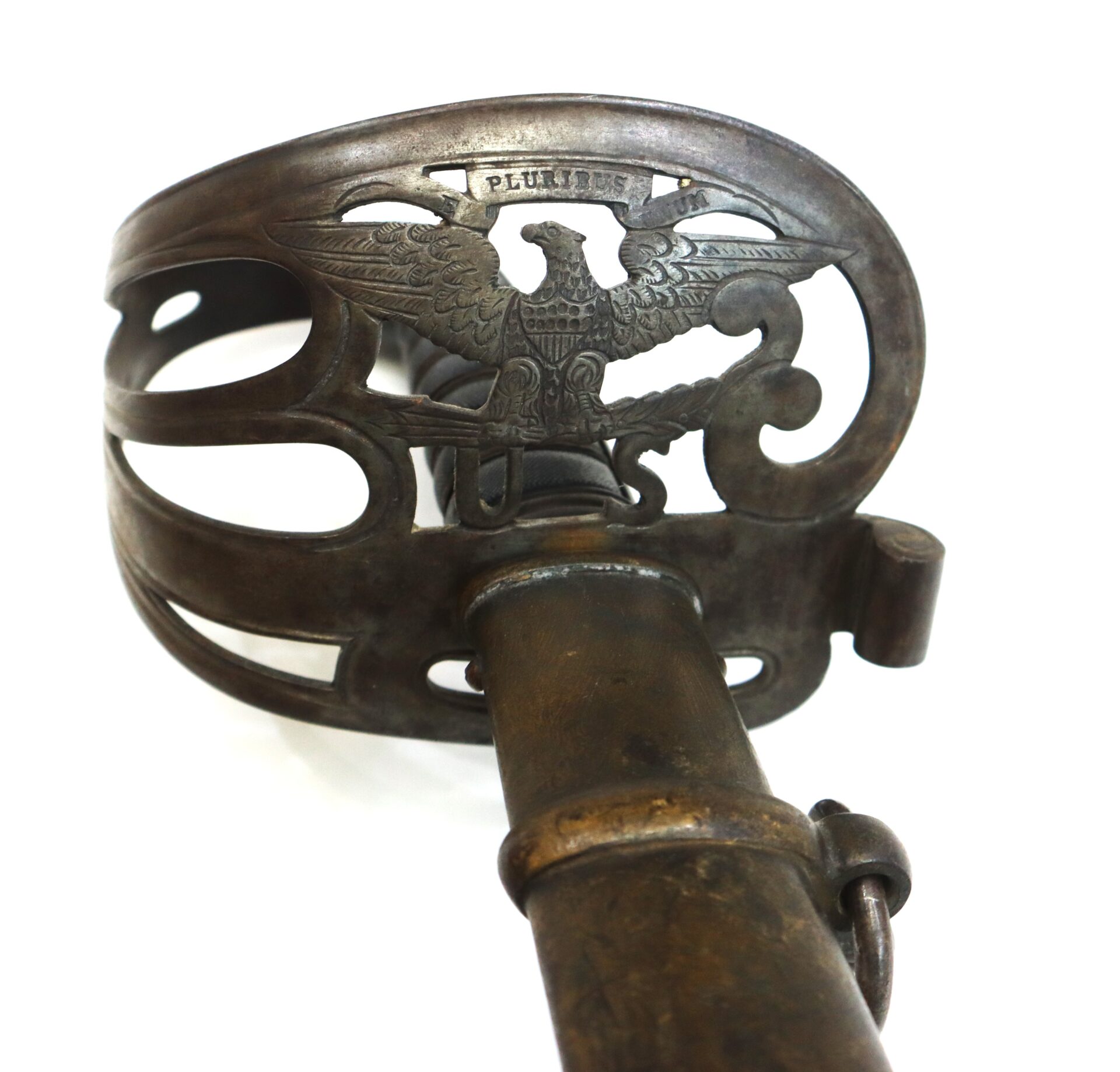 Close-up of a metal sword hilt featuring an eagle design and the word "PLURIBUS" engraved above it, against a white background.