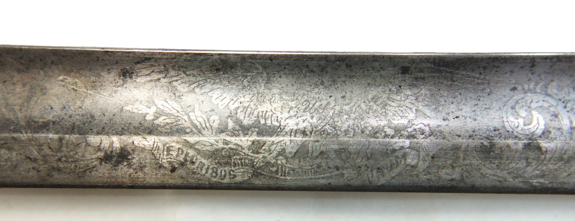 Close-up of an engraved metal sword blade, featuring decorative floral patterns and an eagle design with the date "1815" visible among the etchings.