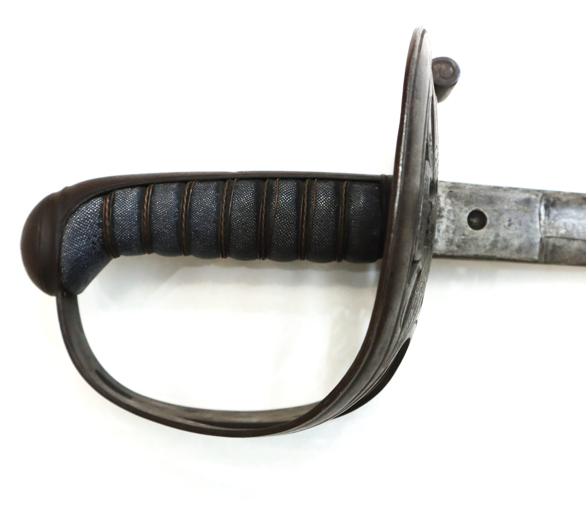 Close-up of the handle and guard of a vintage military sword with a textured grip and metal hand protection.