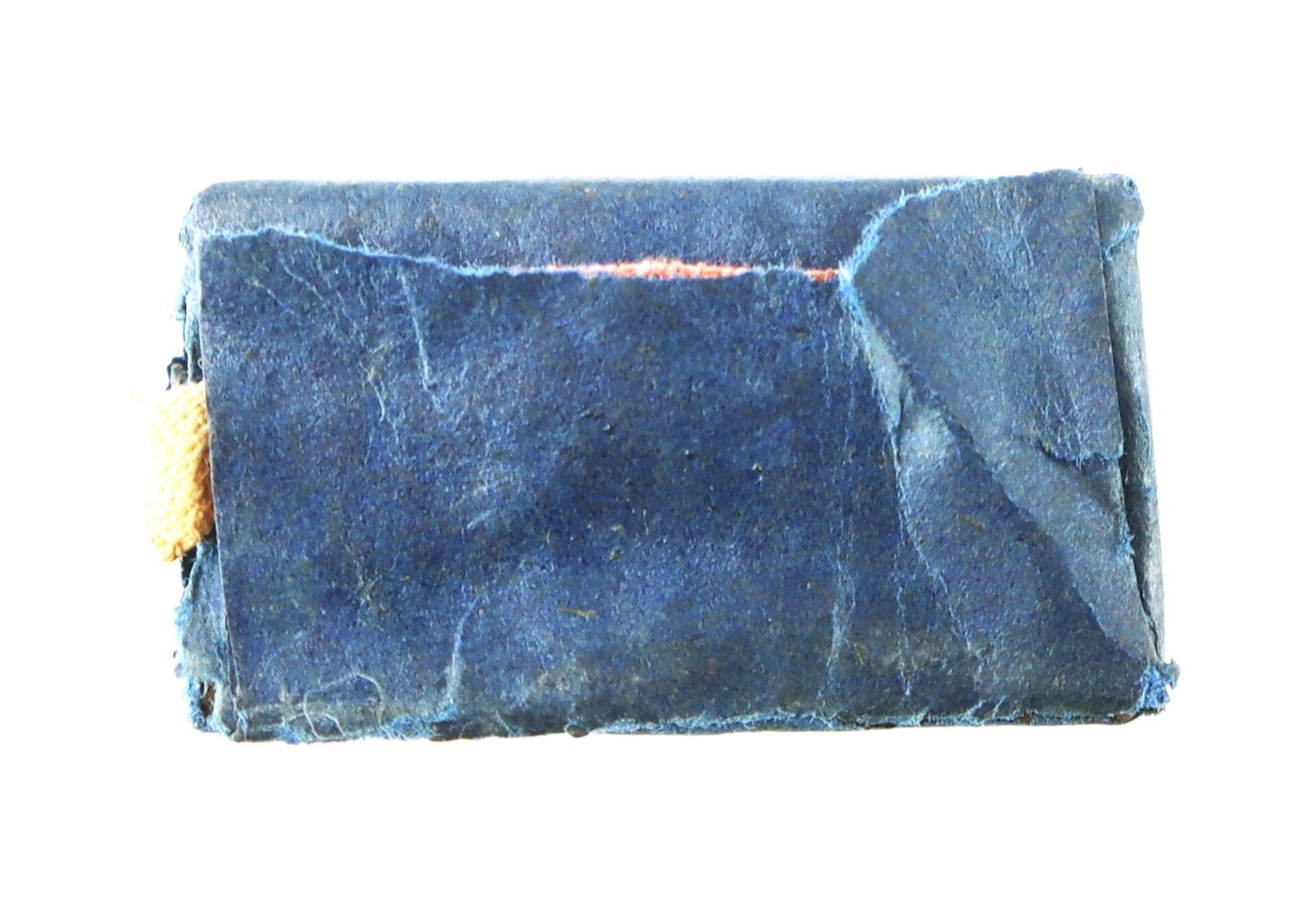 A small, rectangular object wrapped in worn blue paper with a slight tear, revealing an orange tab on one side, isolated on a white background.