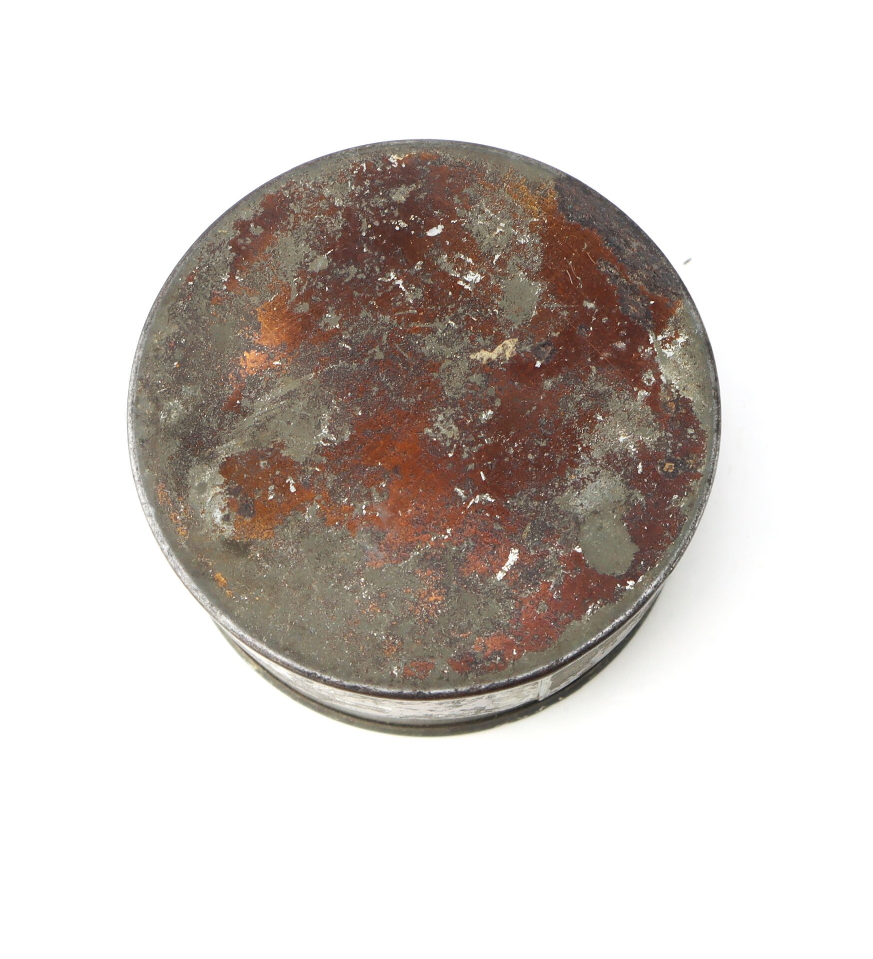 A round, flat metal object with a heavily rusted and corroded surface, viewed from above against a white background.