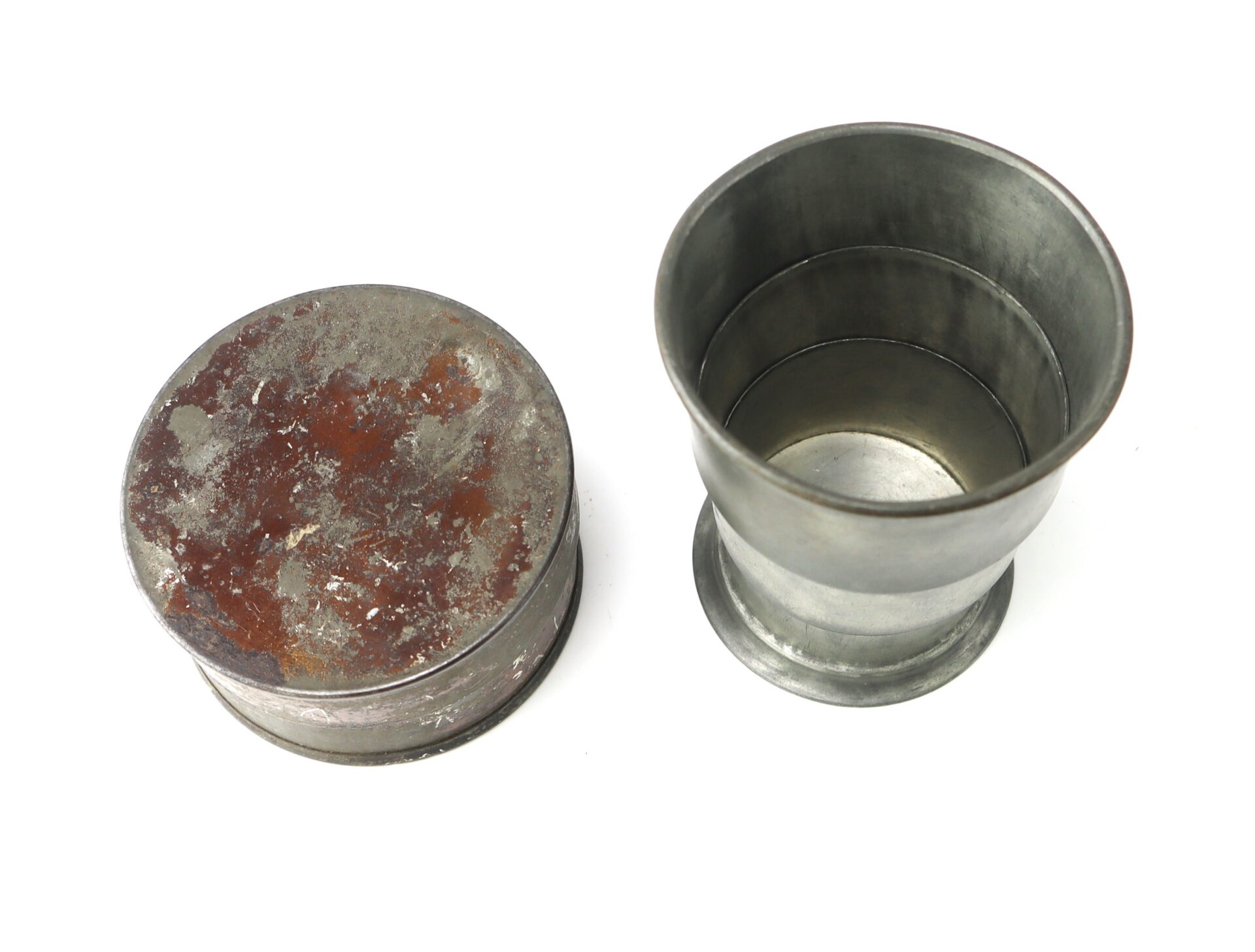 Two metal collapsible cups are shown: one is fully expanded, and the other is collapsed with a worn, rusted surface visible on its base.