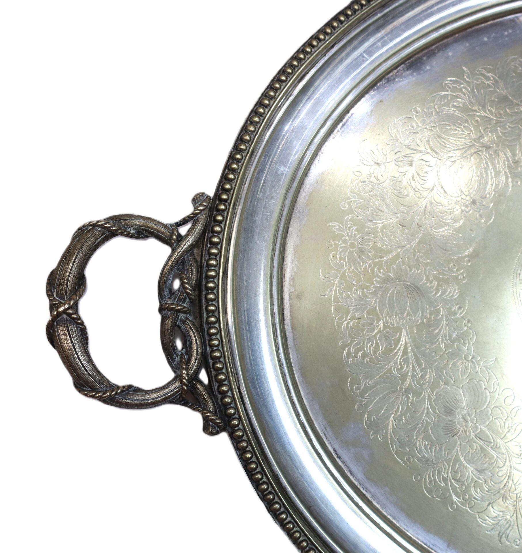 Close-up of an ornate silver tray with a decorative handle and engraved floral patterns on the surface.