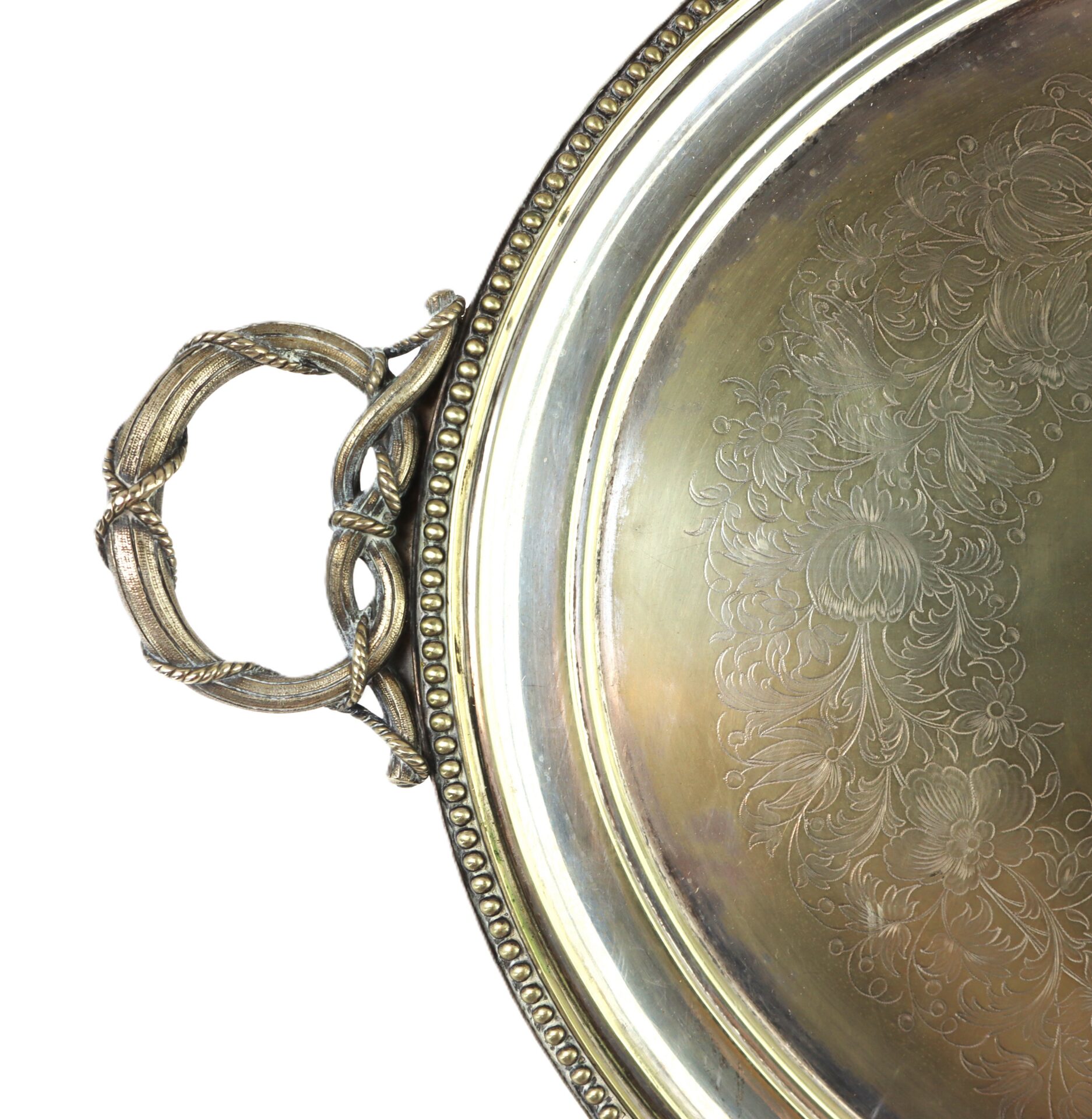 Close-up of an ornate silver or brass serving tray with an engraved floral pattern and a decorative handle on the left side.