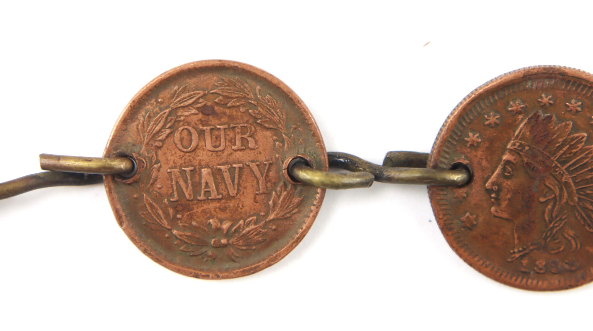 A close-up of two linked coins; one coin displays the text "OUR NAVY" framed by a wreath, while the other shows a profile and stars.