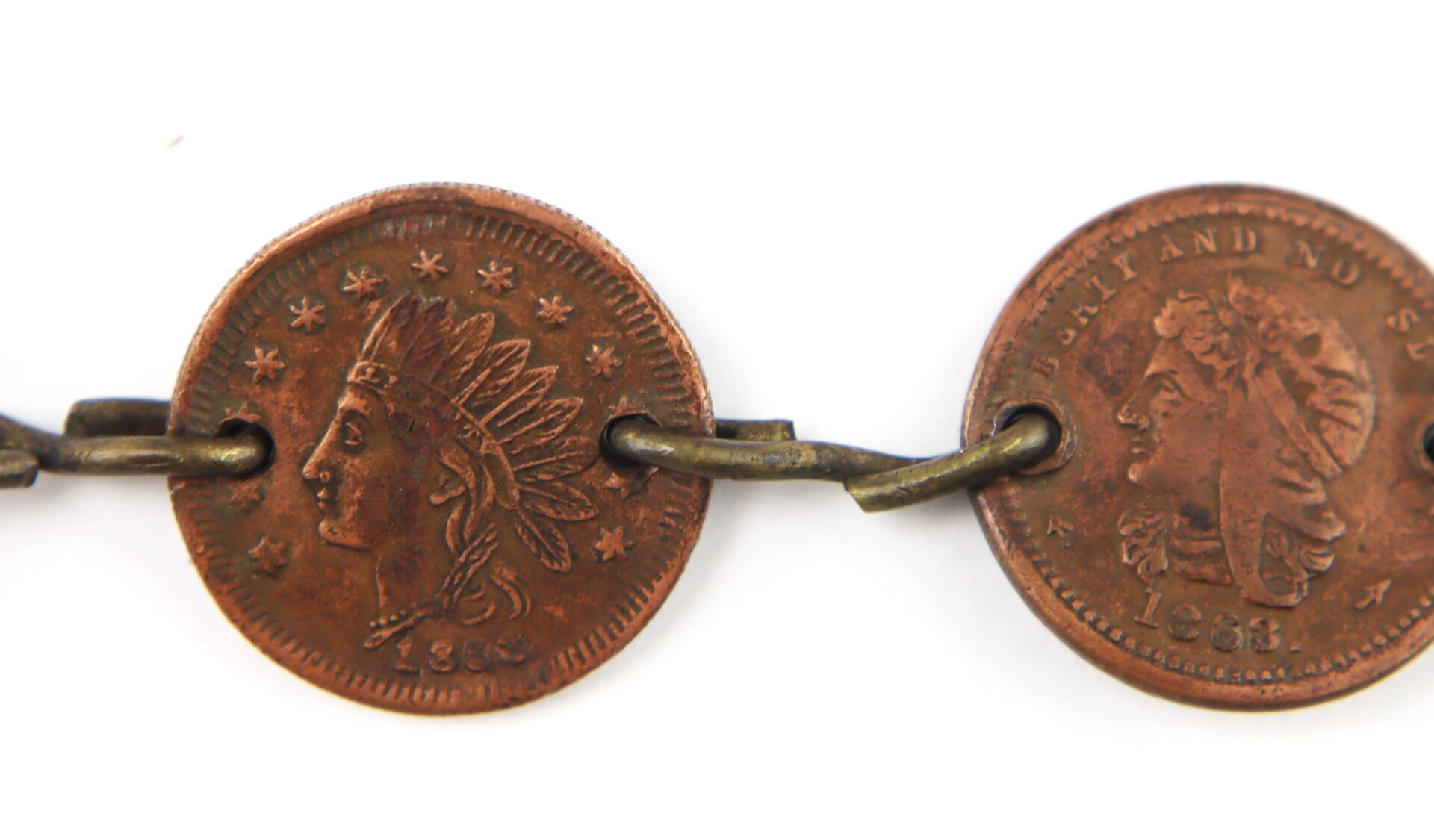 Two old copper coins with holes linked by a metal chain; the left coin displays a Native American head and the date 1889.
