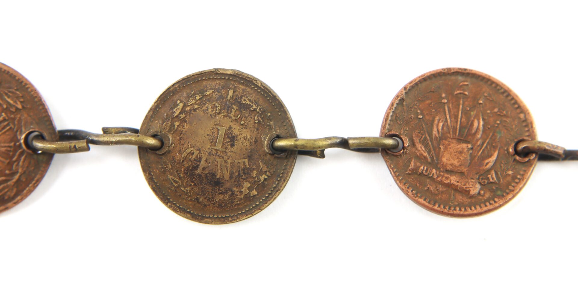Three worn copper coins with visible inscriptions are linked together by metal rings in a chain-like arrangement.