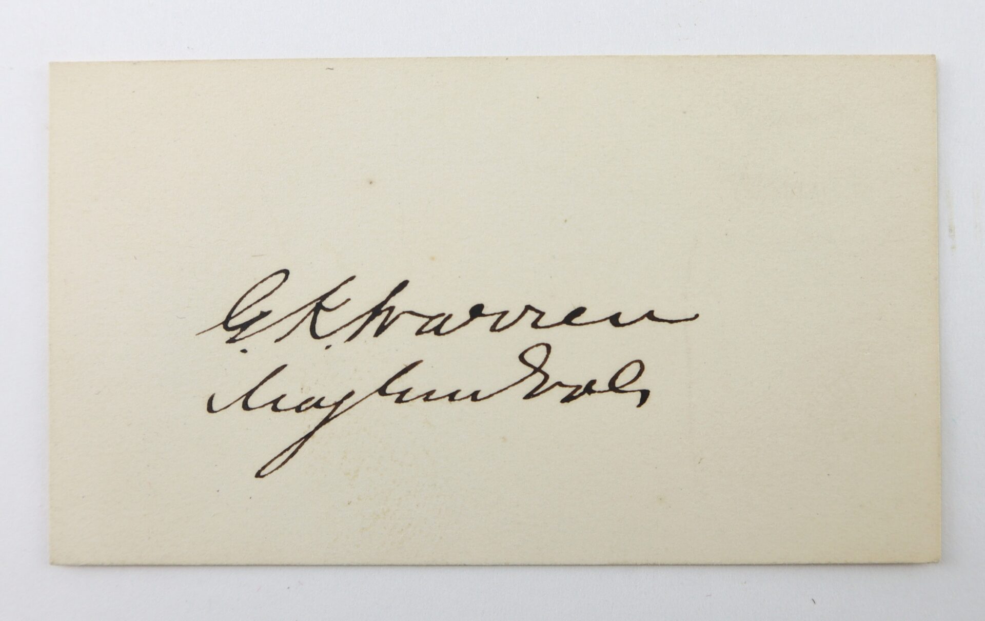 A cream-colored card with two lines of black handwritten cursive, possibly a signature, centered on the card.