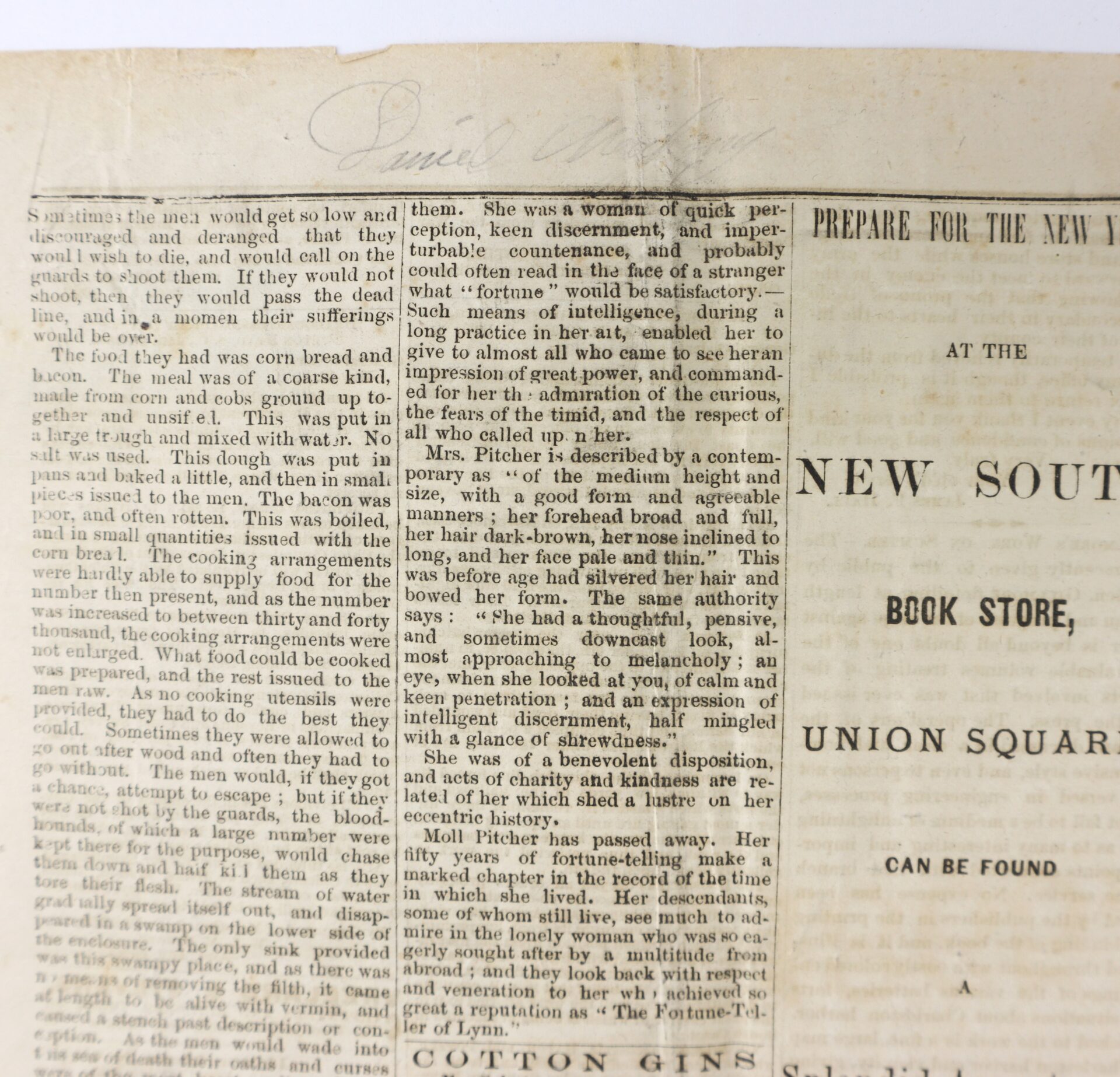 A close-up of an old newspaper page with printed text and faint handwritten words at the top of the page.