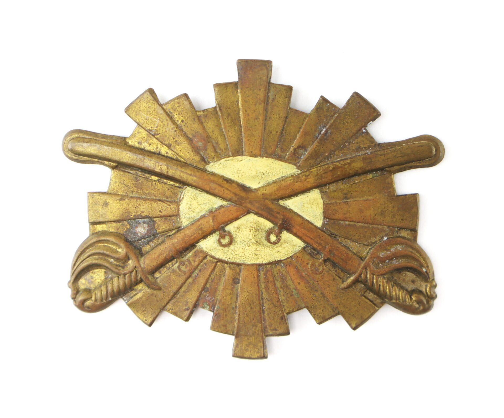 A vintage brass military badge featuring two crossed swords over a sunburst design with an oval center.