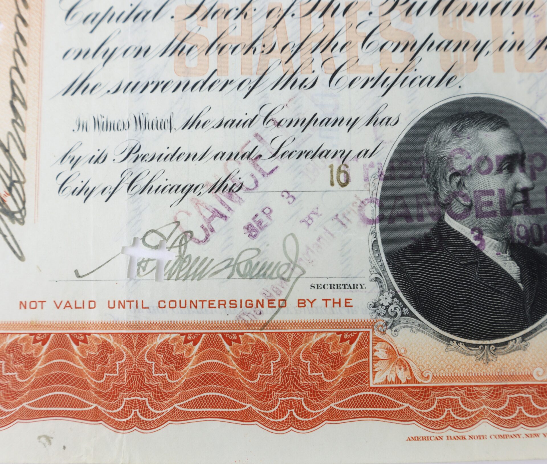 Close-up of a stock certificate featuring text, a signature, a sepia-toned portrait, various stamps including "CANCELLED," and a red border with the words "NOT VALID UNTIL COUNTERSIGNED.