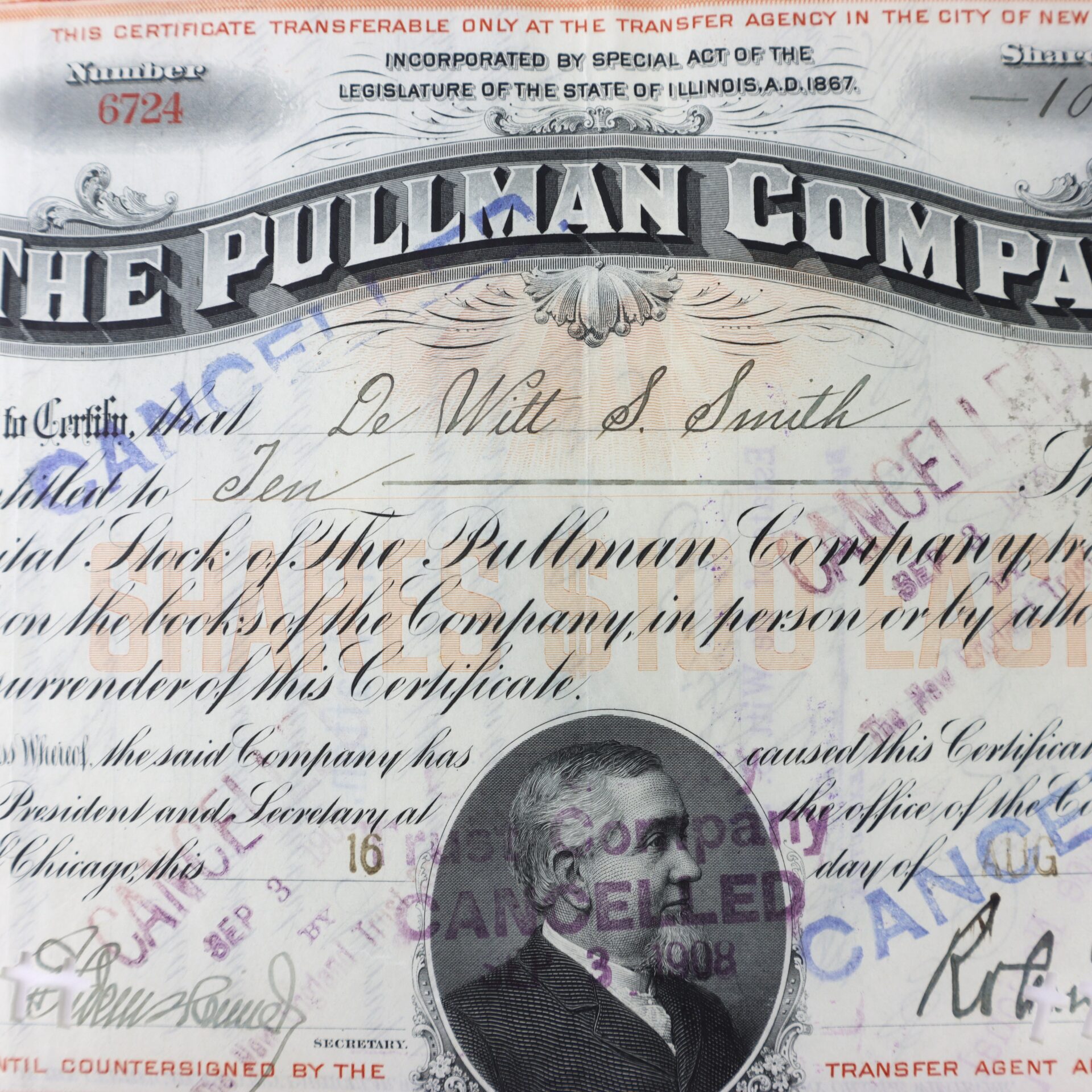Close-up of a vintage Pullman Company stock certificate with handwritten details, official stamps, and a portrait of a man in the center. The document is marked "CANCELLED.