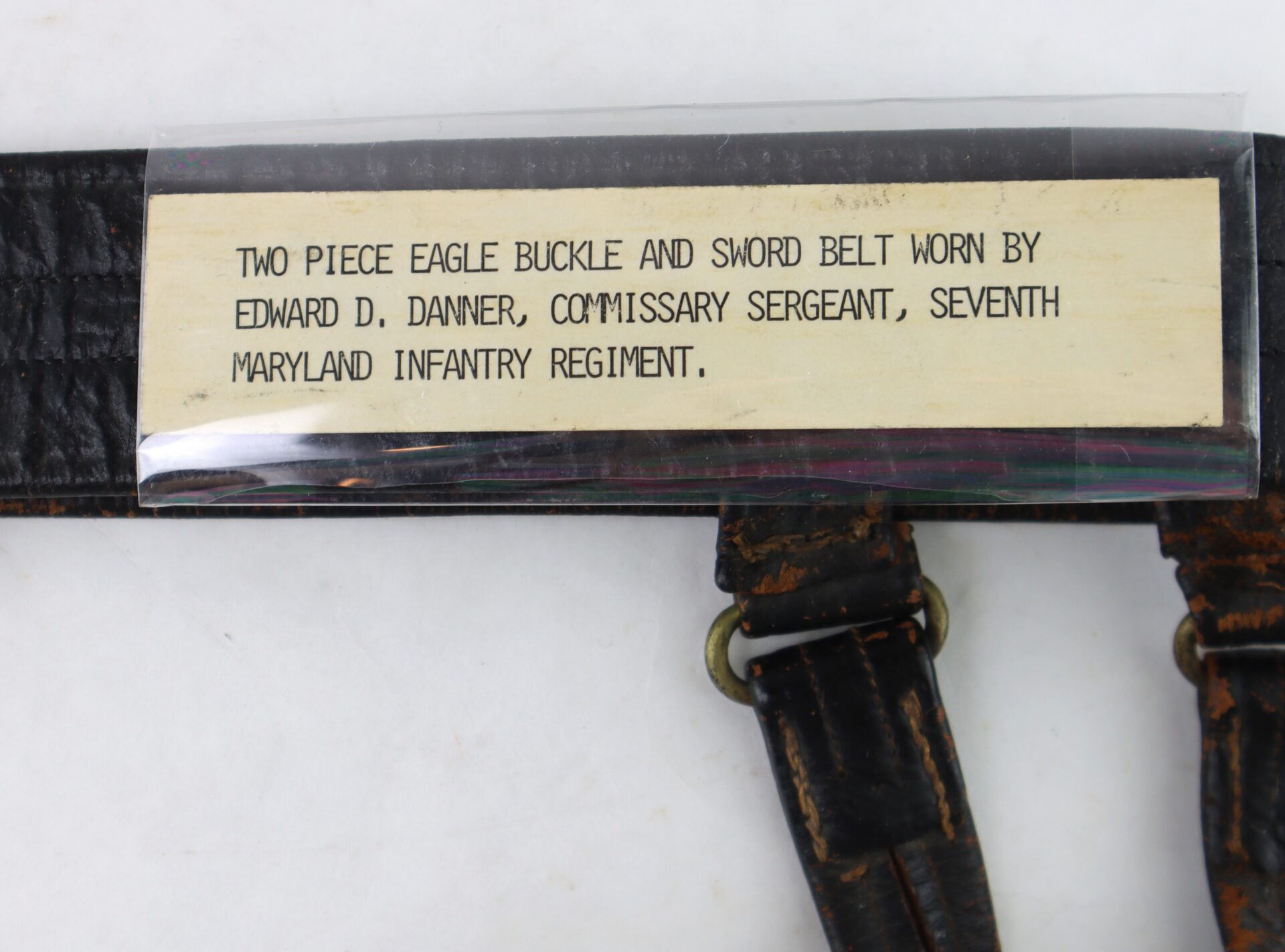 A label reads: "Two piece eagle buckle and sword belt worn by Edward D. Danner, Commissary Sergeant, Seventh Maryland Infantry Regiment." The belt is partially visible below the label.