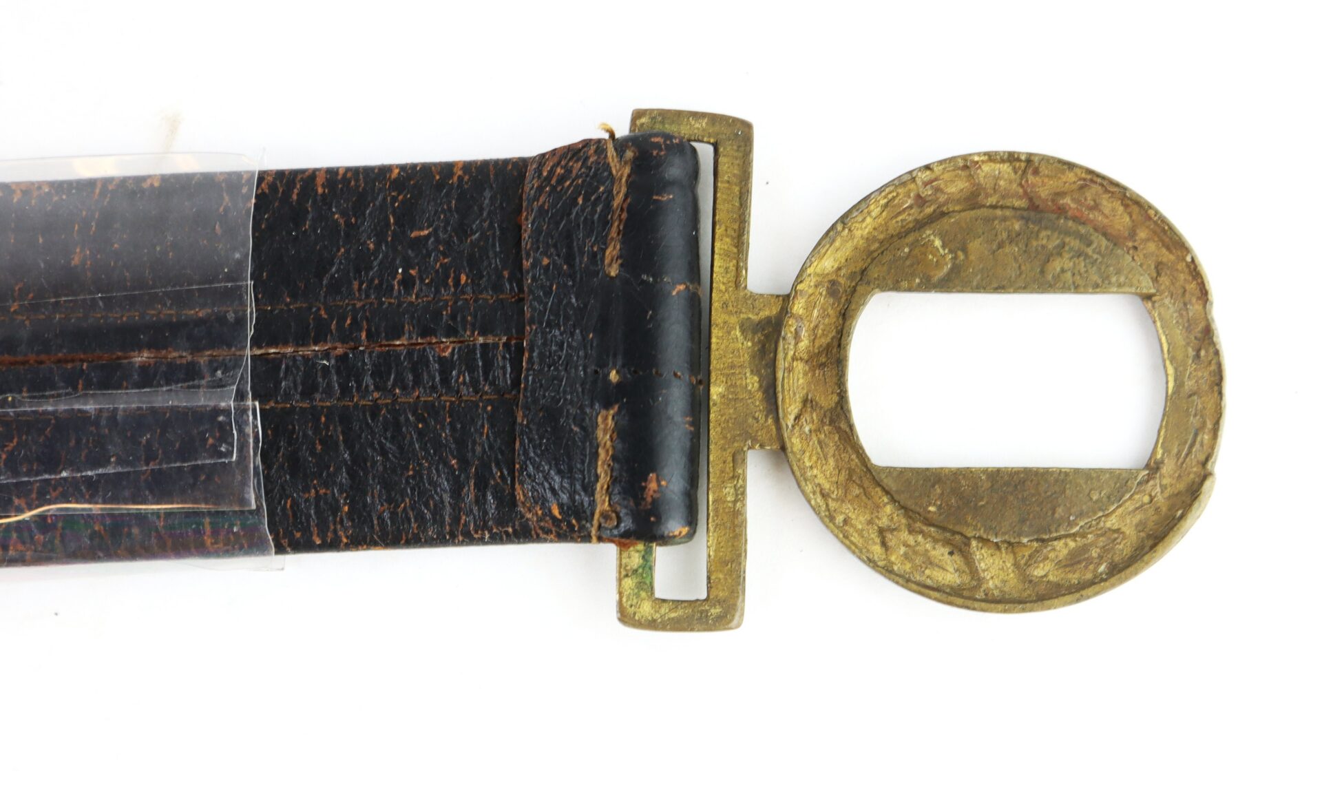 Close-up of a worn leather belt with a large, round, brass buckle featuring an open rectangular slot in the center.
