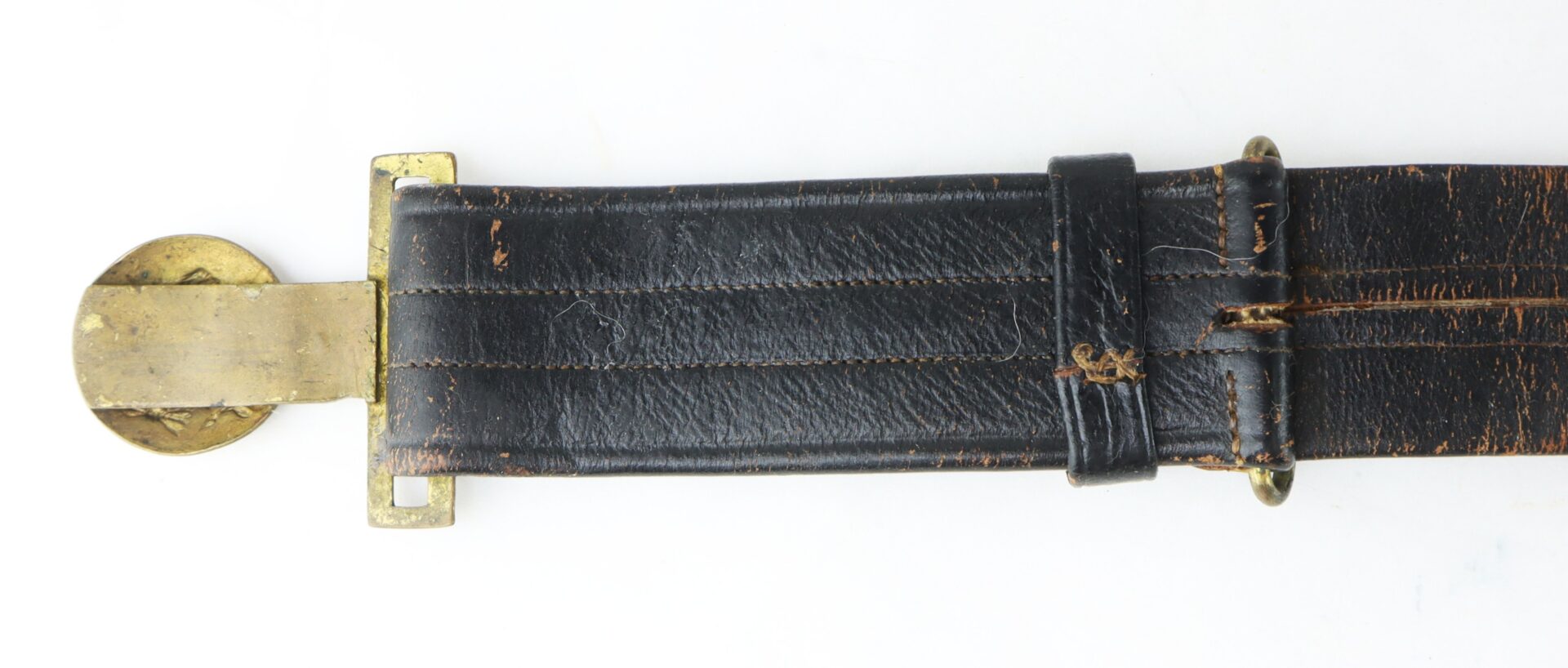 A worn black leather belt with visible stitching, brass rectangular buckle, and a round brass disc on a white background.