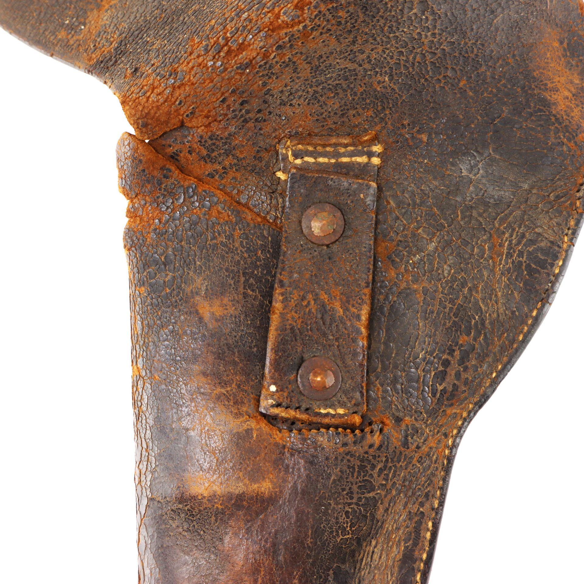 Close-up of a weathered, cracked brown leather object with a stitched strap and two rusty metal rivets.