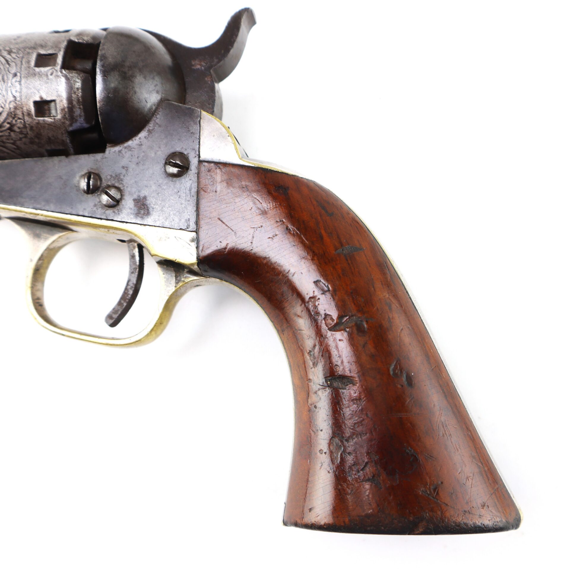 Close-up of the wooden grip and trigger of an antique revolver with visible wear and scratches on the handle.