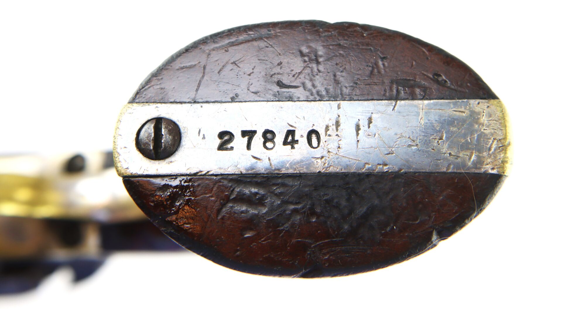 Close-up of a worn wooden object with a metal plate attached by a screw, engraved with the number 27840.
