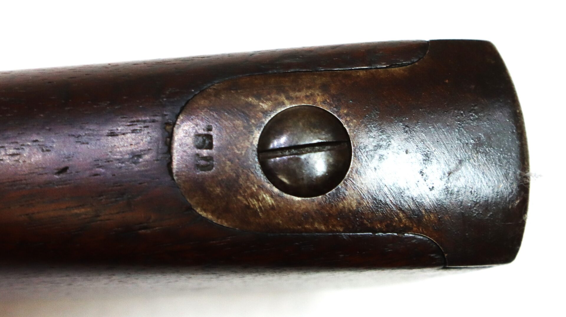 Close-up of a worn, dark wooden object with a large flathead screw in the center and faint markings beside it.