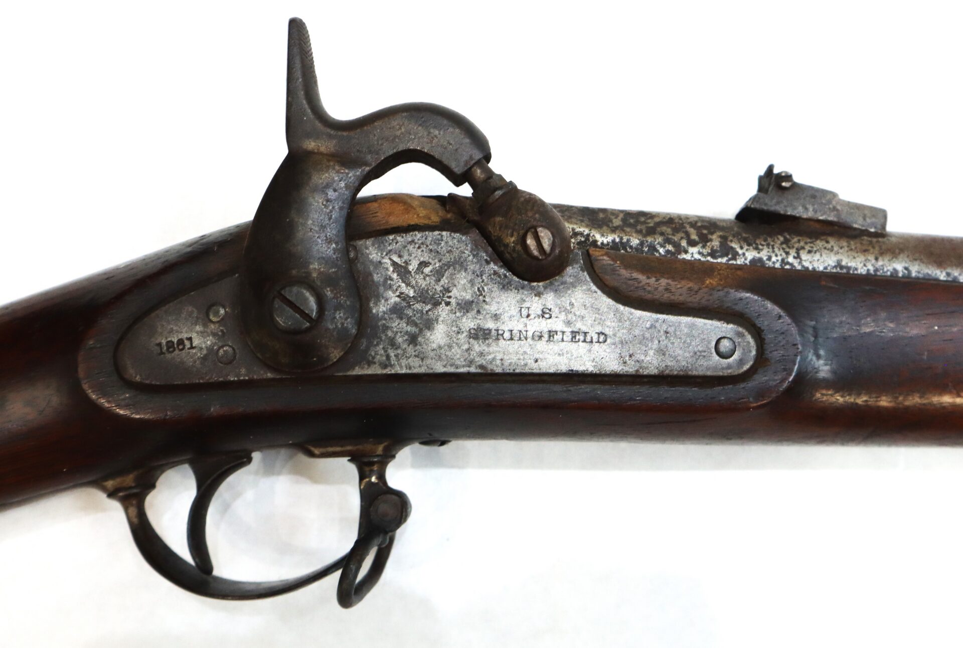 Close-up of an antique Springfield rifle lockplate, showing the hammer, trigger, and engraved markings "1861" and "U.S. SPRINGFIELD.