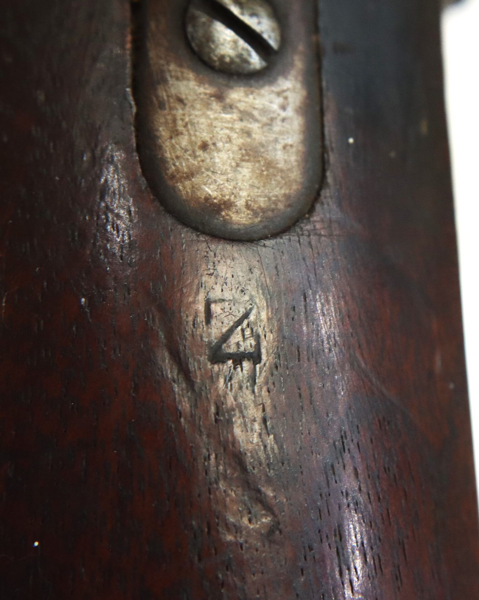 Close-up of a wooden surface with a carved number "4" and a metal screw partially visible at the top.