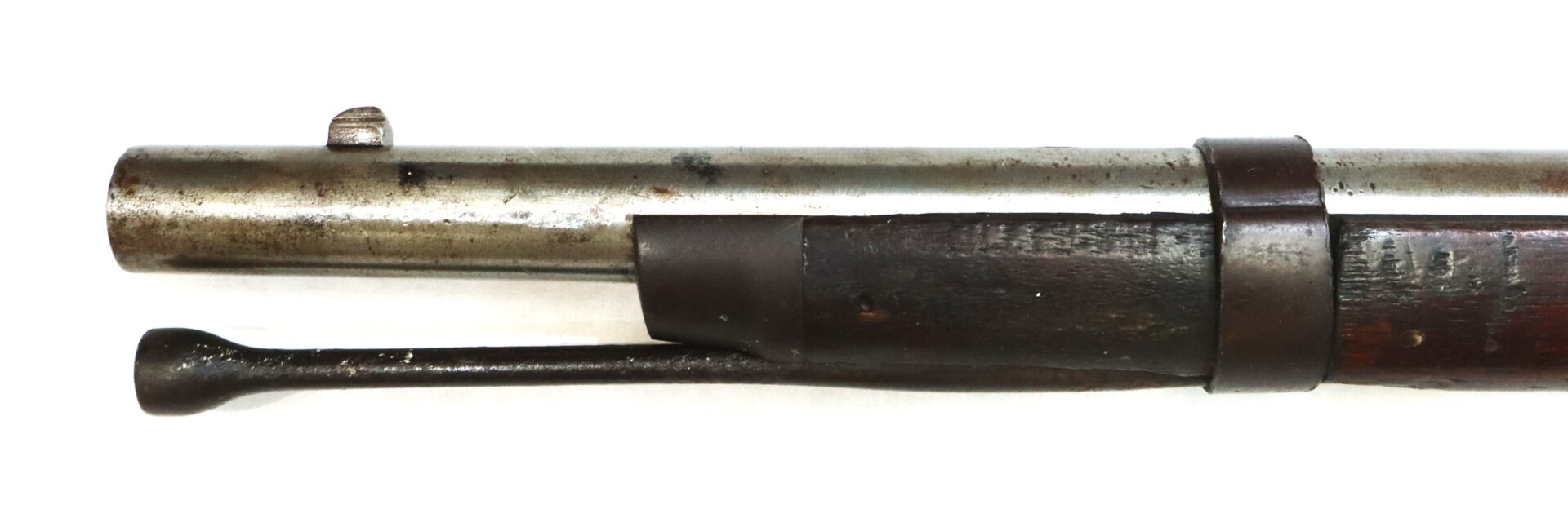 Close-up of the muzzle and front barrel band of an old bolt-action rifle, showing part of the wooden stock and a metal cleaning rod underneath the barrel.