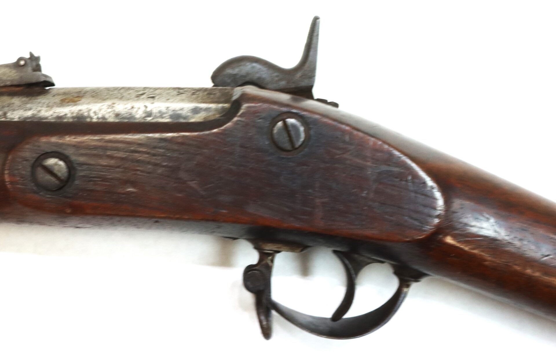 Close-up view of the wooden stock, trigger, and hammer mechanism of an antique flintlock or percussion rifle against a white background.