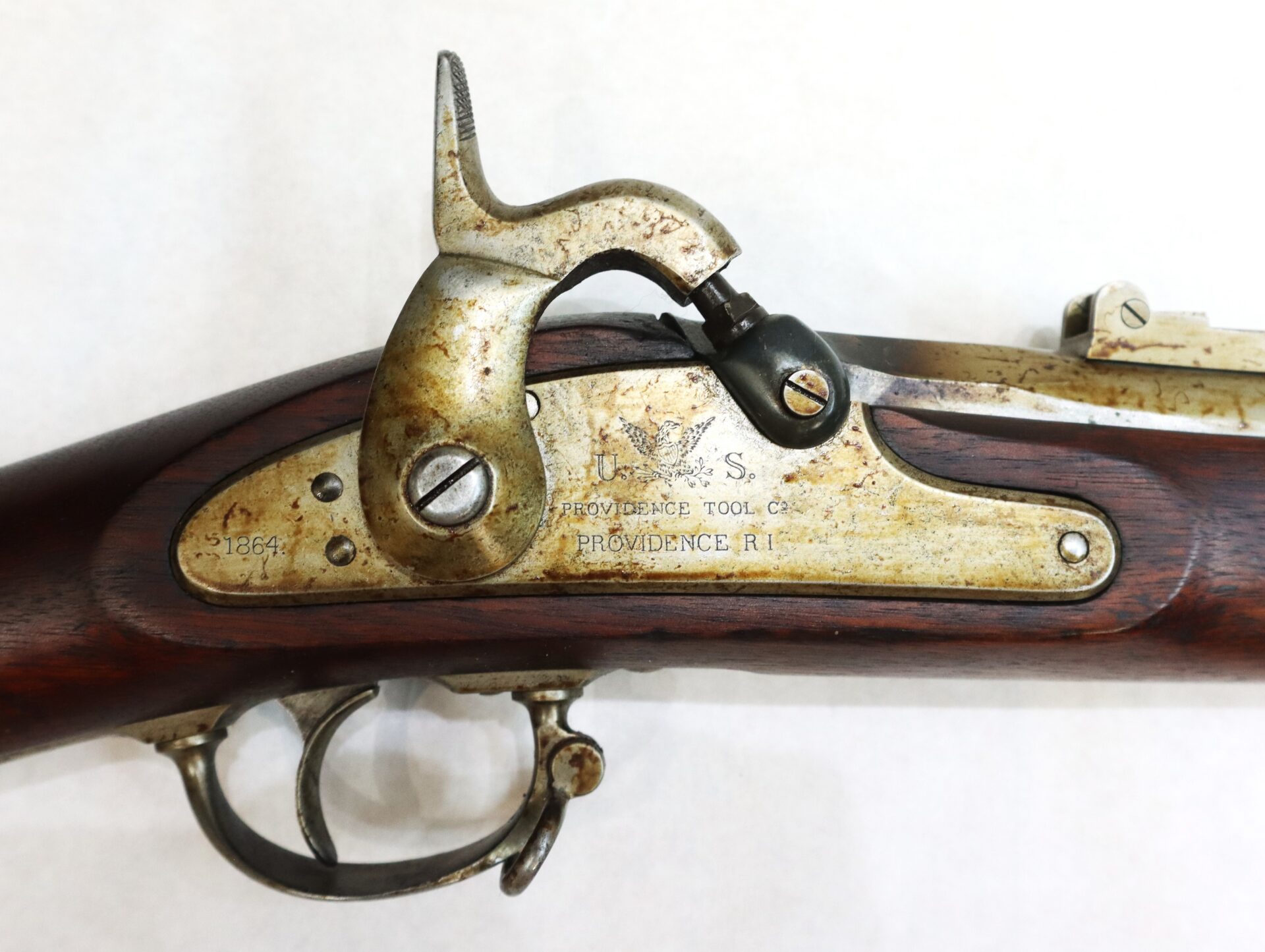 Close-up of the lock mechanism and trigger area of an antique rifle marked "U.S. Providence Tool Co. Providence R.I." with visible wear and patina on the metal parts.