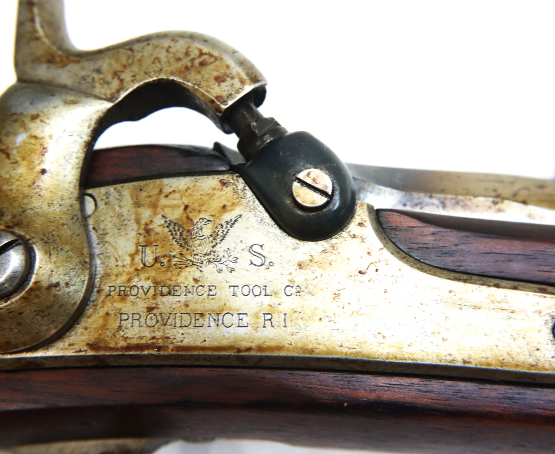 Close-up of an antique firearm marked "U.S." with an eagle emblem and text reading "PROVIDENCE TOOL CO. PROVIDENCE R.I." engraved on the metal plate.